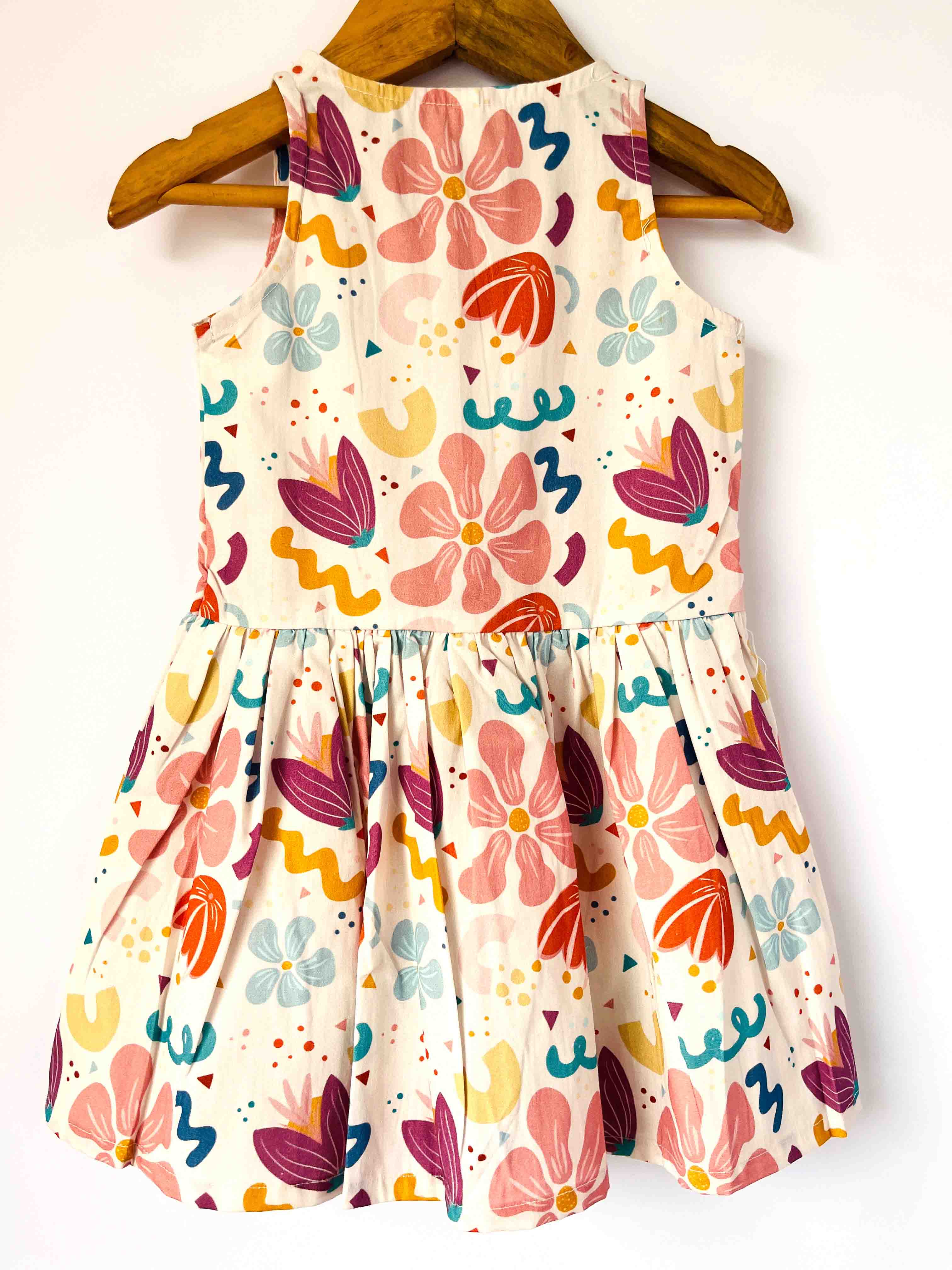 Colorful floral dress on a wooden hanger against a white background