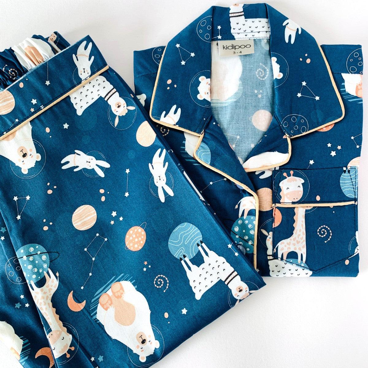 A night suit with long sleeves, featuring an astronaut bear design on a dark blue background with stars and planets.