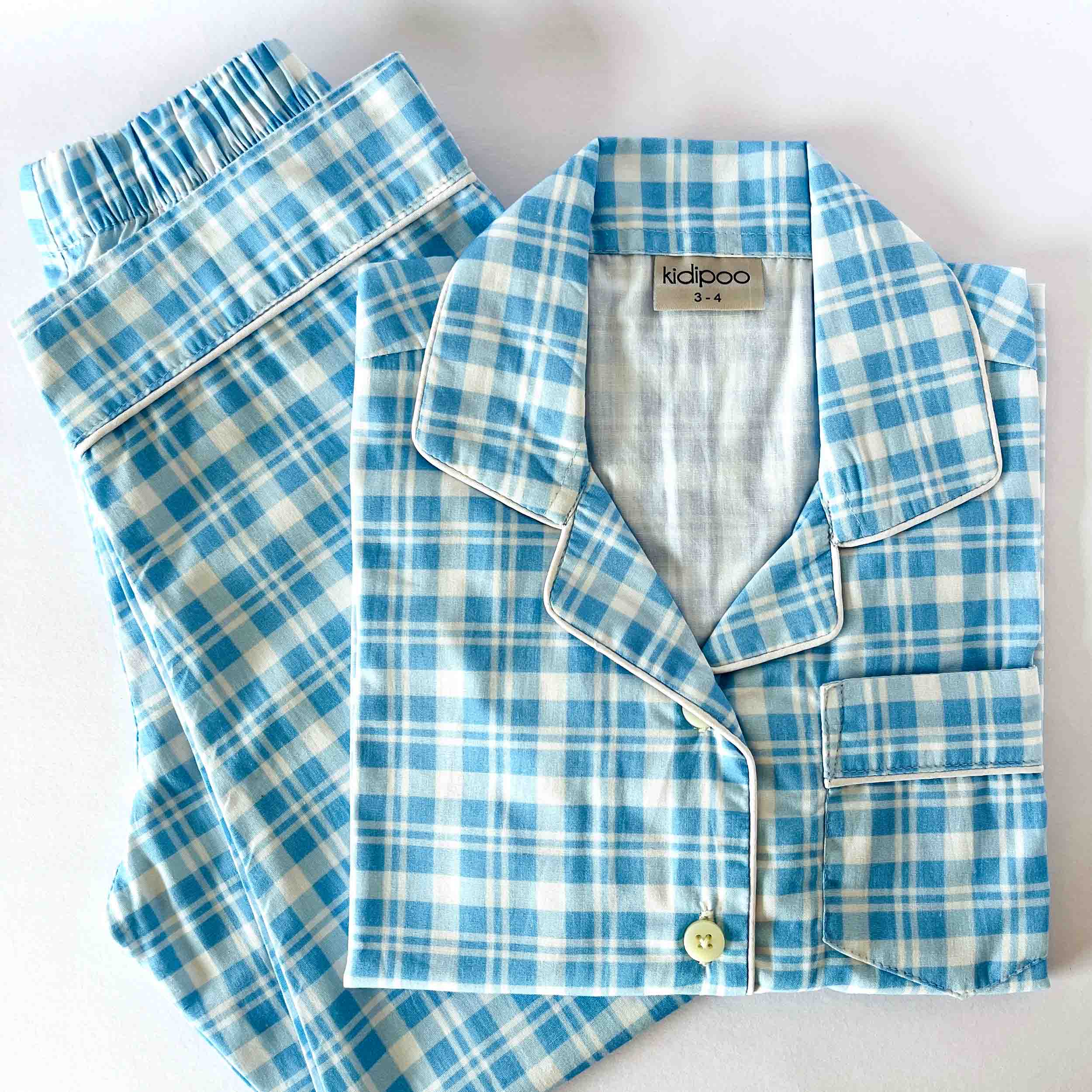 Blue and white checkered pajama set with 'Kidipoo' label on a light background