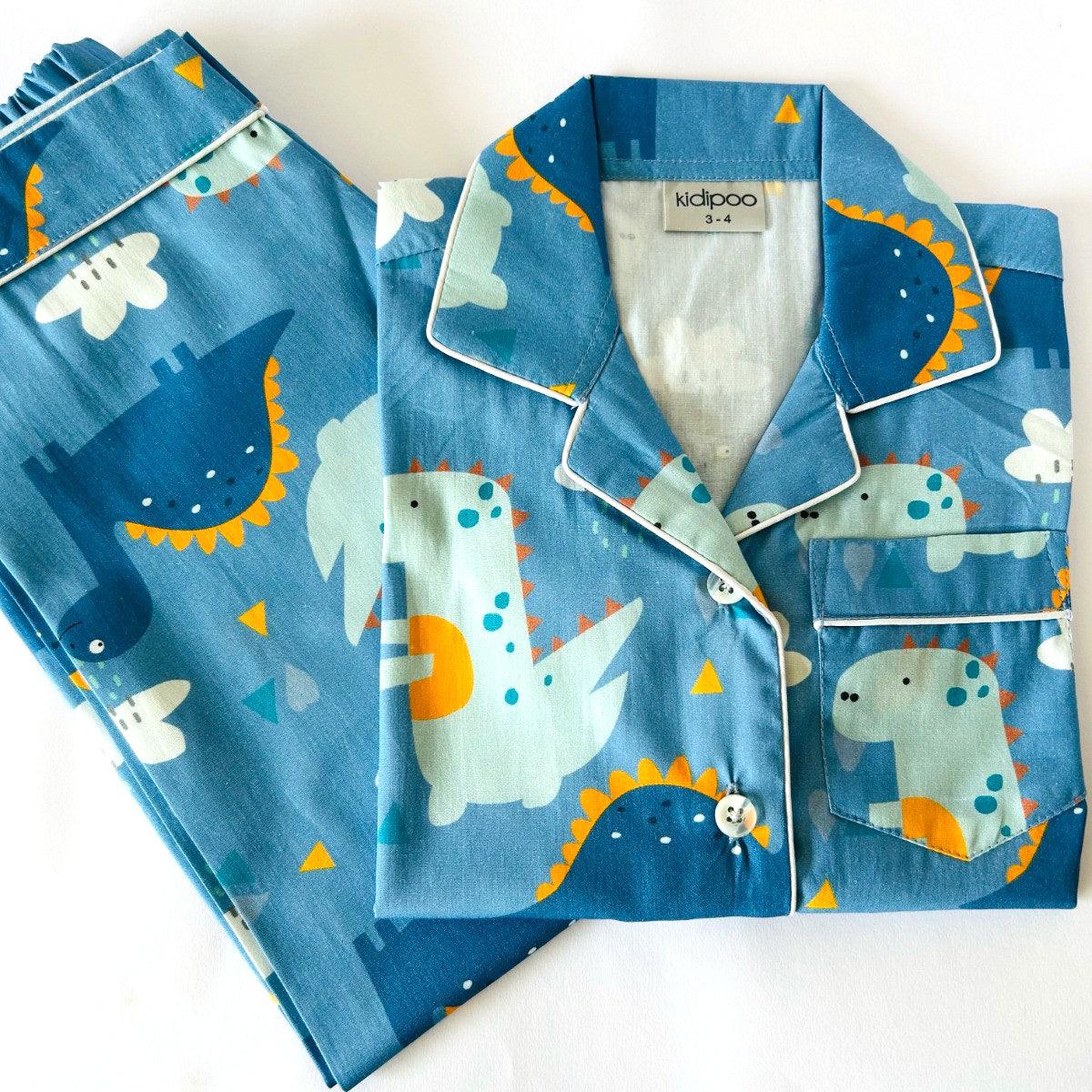 A blue pajama set with dinosaur prints, including a long sleeve, front button shirt and coordinated pajamas with elastic at waist.