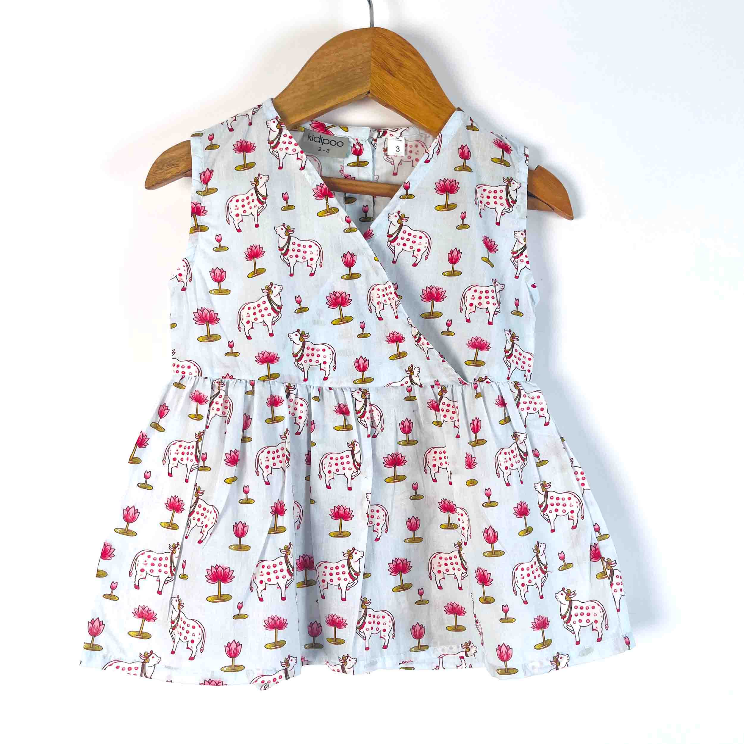 Kids blue Pichwai cotton sleeveless dress with V-neck wrap style, flared fit, and all-over cow and floral print
