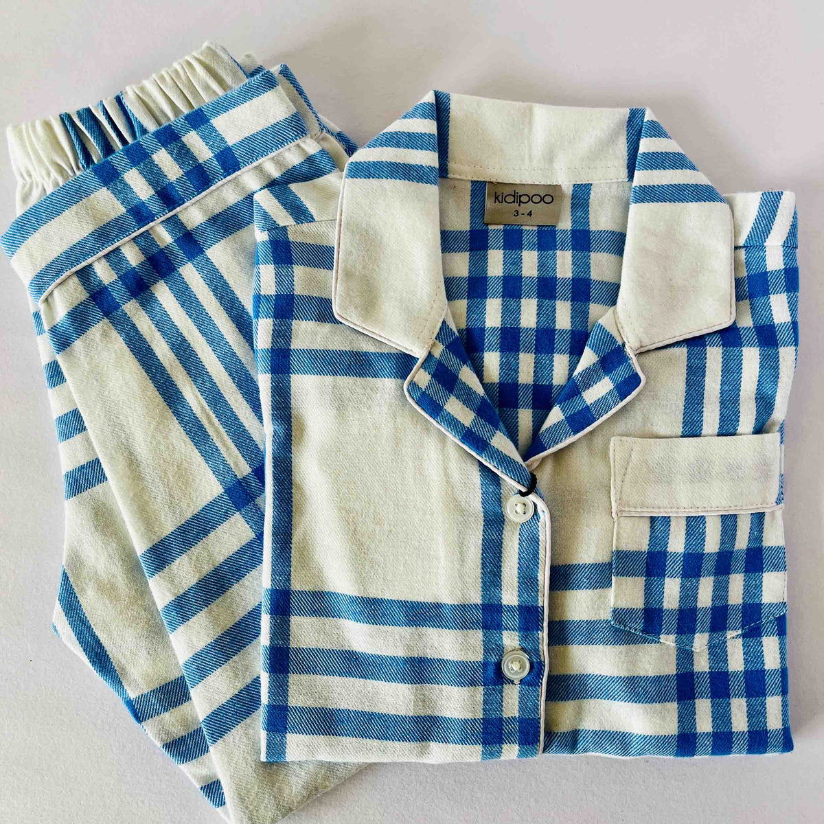 Blue and white checkered pajama set with a shirt and pants on a light gray background