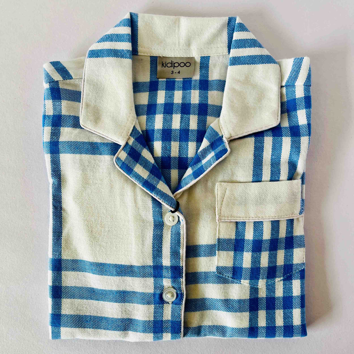 Blue and white checkered shirt with 'kidpoo' label on a light gray background
