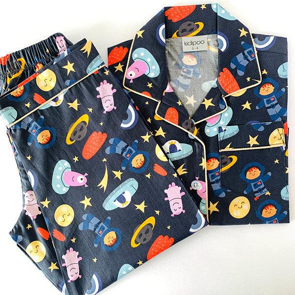 A set of children's night suit with long sleeves, featuring a space-themed print with characters and planets on a dark background.