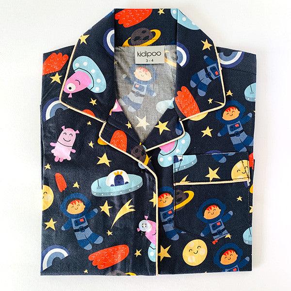 A set of children's night suit with long sleeves, featuring a space-themed print with characters and planets on a dark background.