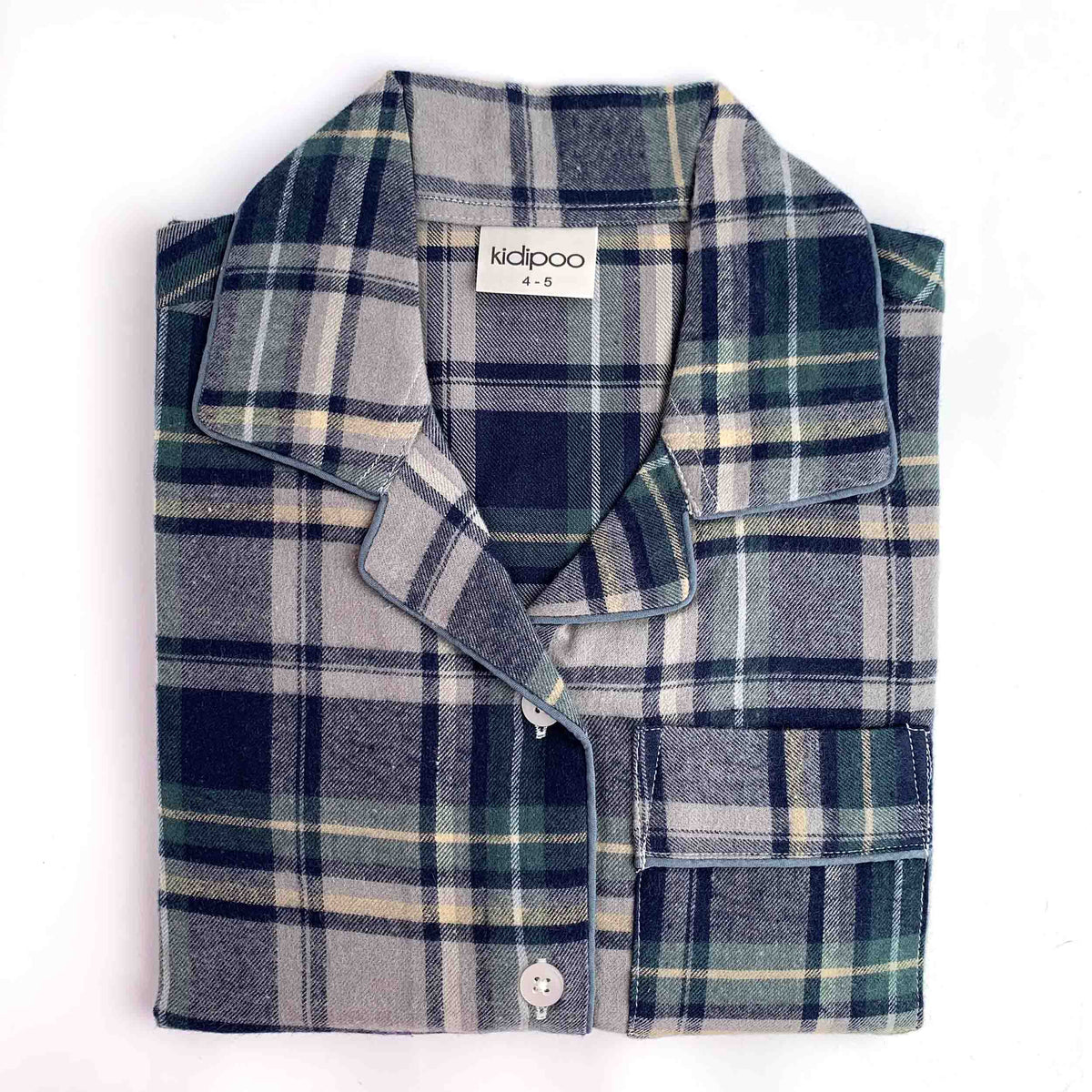 A folded plaid pajama shirt with a collar and button front, shown on a plain white background. The shirt features a pattern of navy, gray, green, and beige.