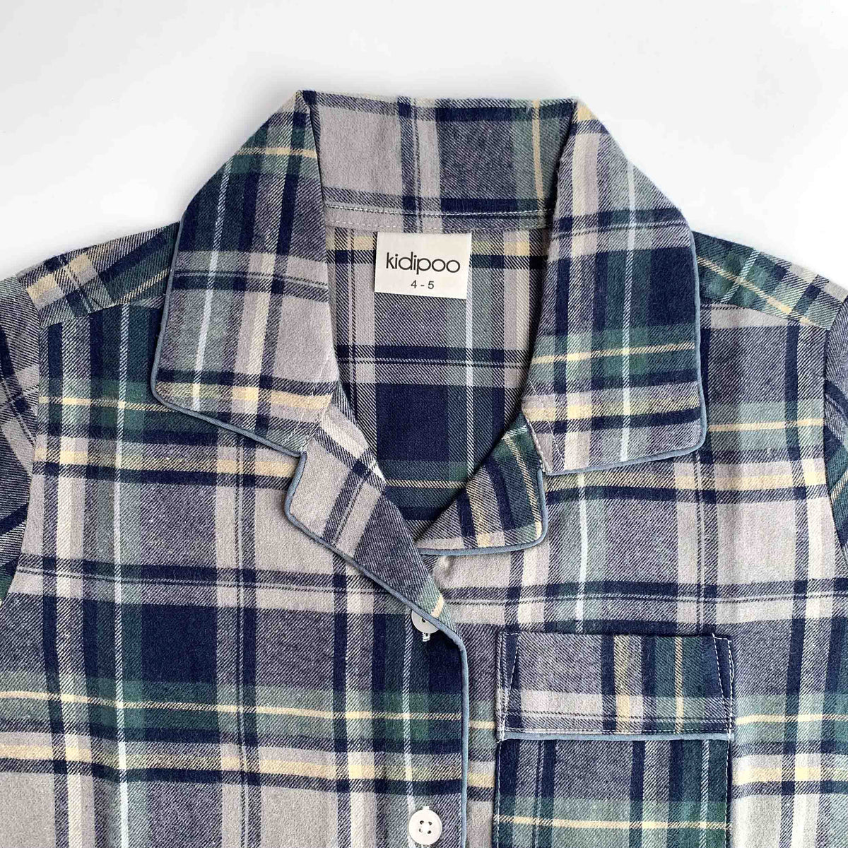 A close-up of a children's long-sleeve plaid shirt by kidpoo, featuring a navy, green, and beige plaid pattern with a collar and button-down front.