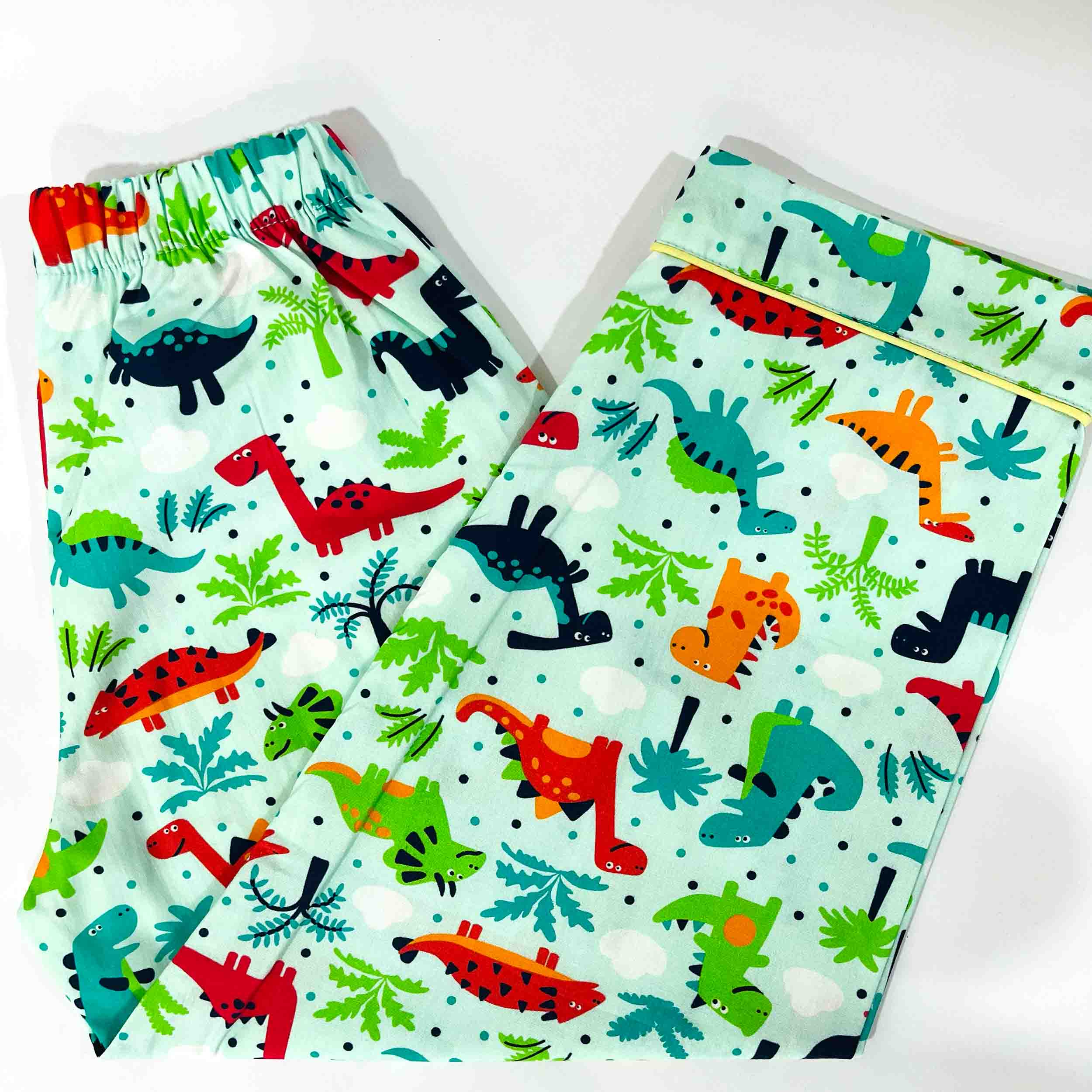Children's pajama set with colorful dinosaur pattern on a light blue background