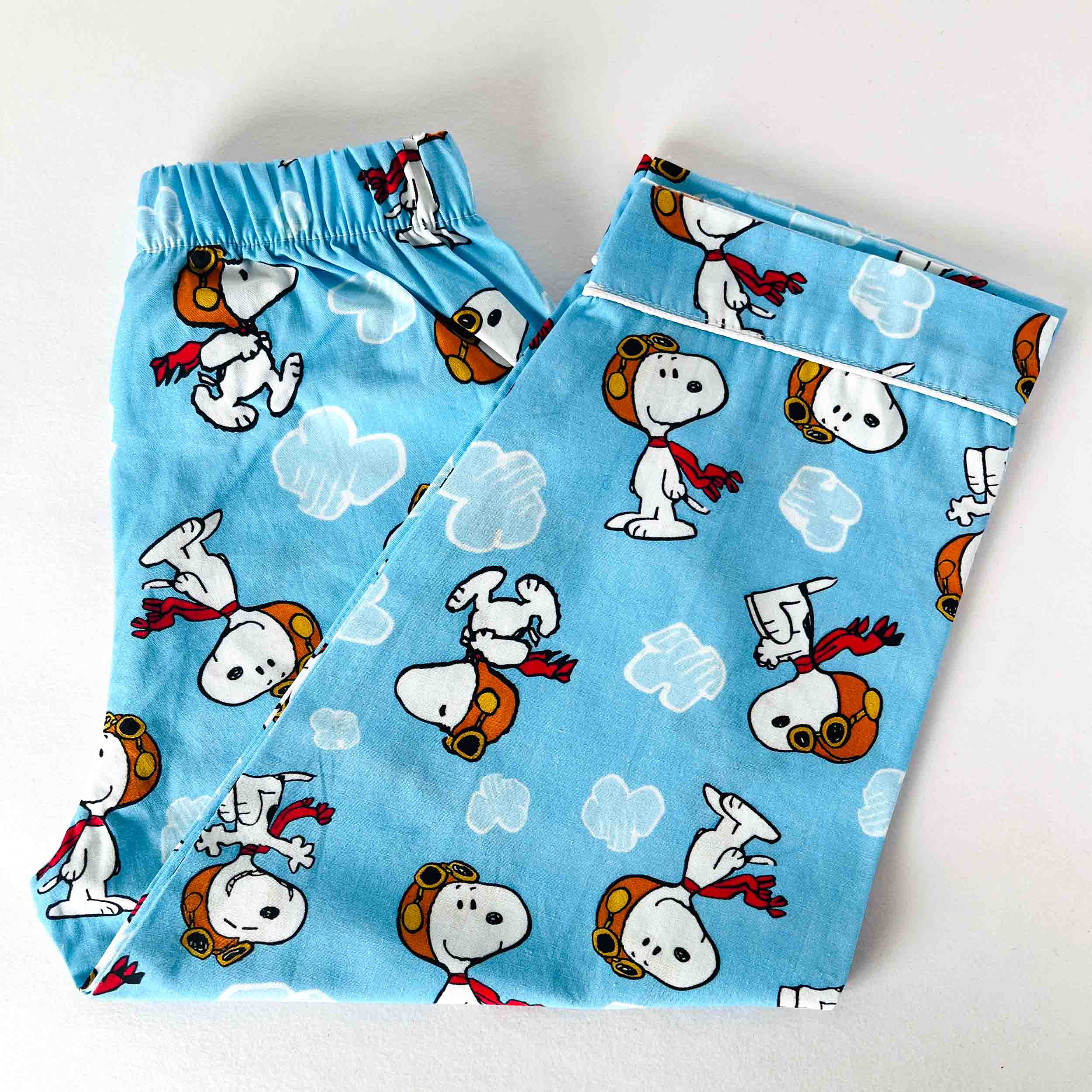 Pair of blue pajama pants with cartoon character pattern on a white background