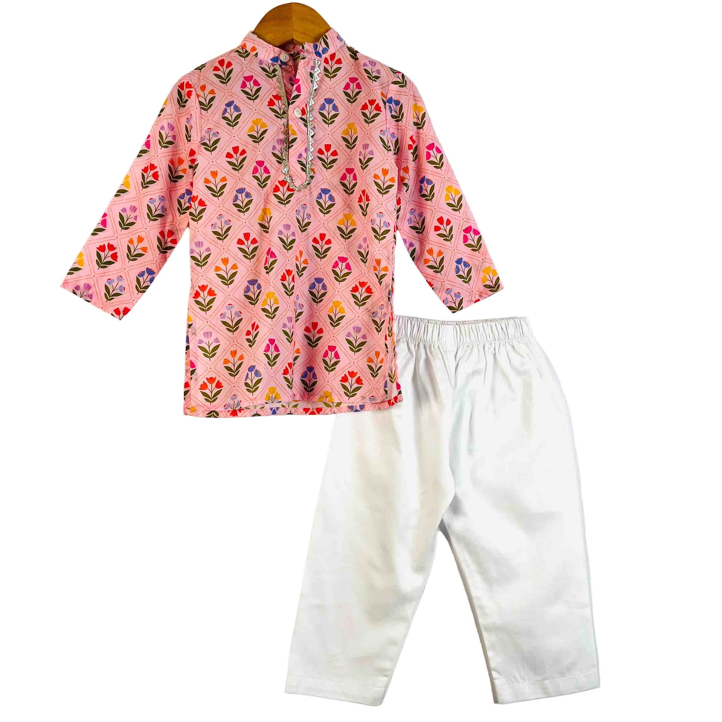 A children's two-piece outfit set featuring a pink long-sleeve kurta with a colorful floral print and white pants, displayed on a wooden hanger against a white background.