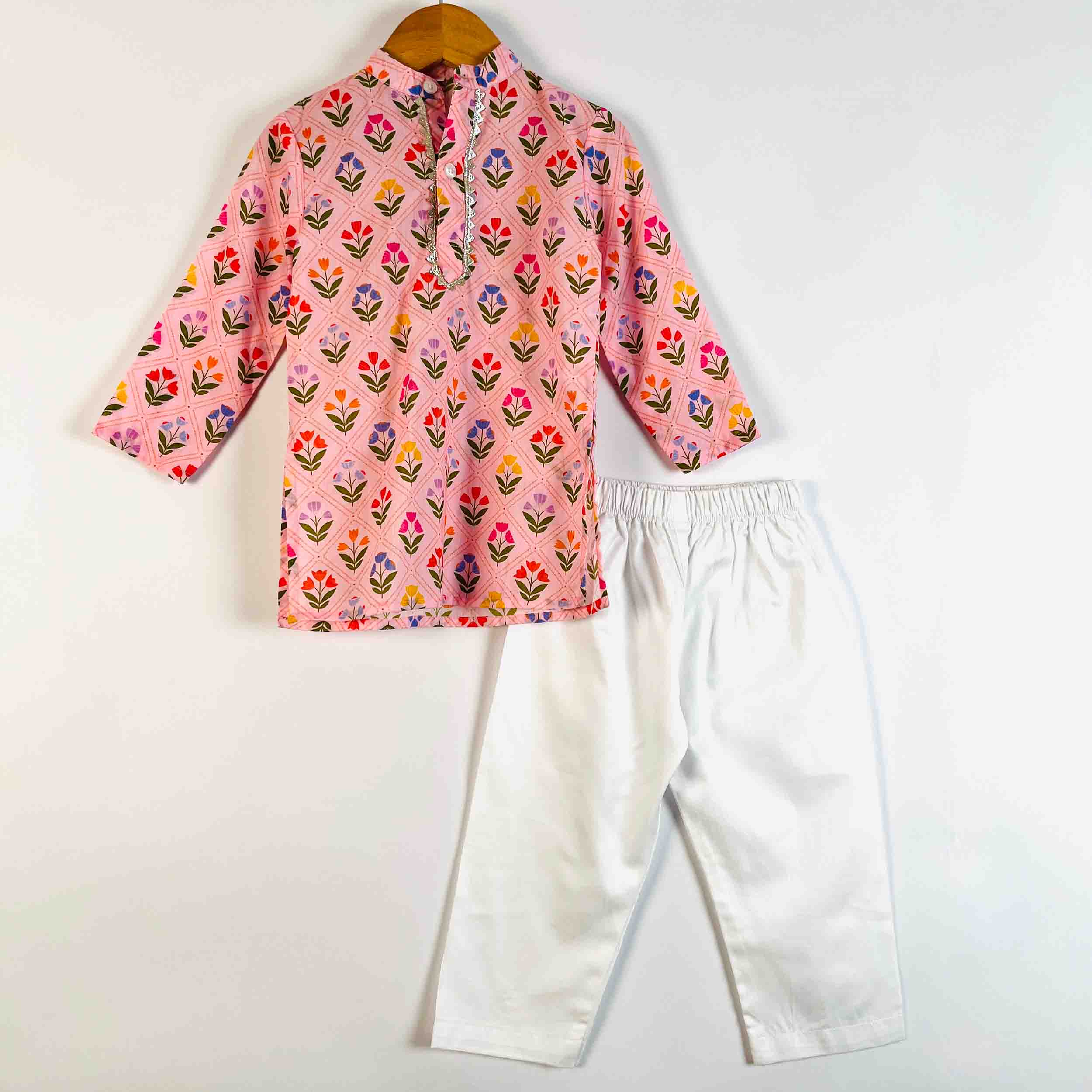 A children's two-piece outfit set featuring a pink long-sleeve shirt with a colorful floral print and white pants, displayed on a wooden hanger against a plain white background.