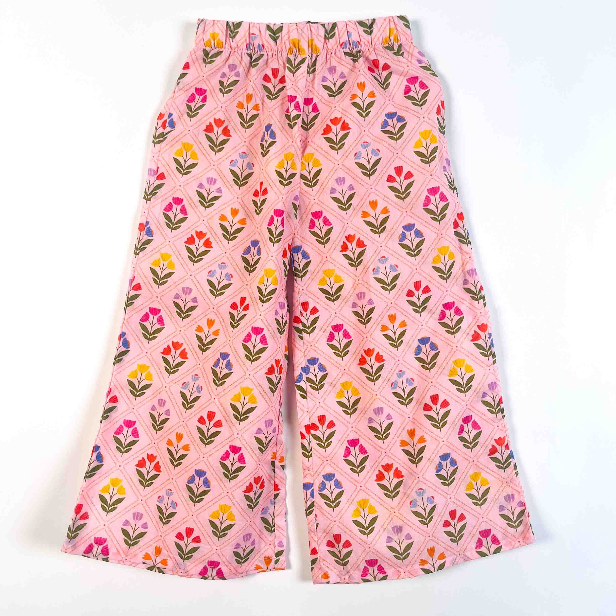 Pink wide-leg cropped pants with a colorful floral block print pattern, laid flat on a white background.