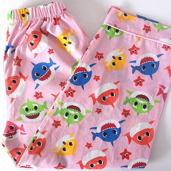 A children's pajama set with long sleeves, featuring a pink background with colorful shark characters and star patterns.
