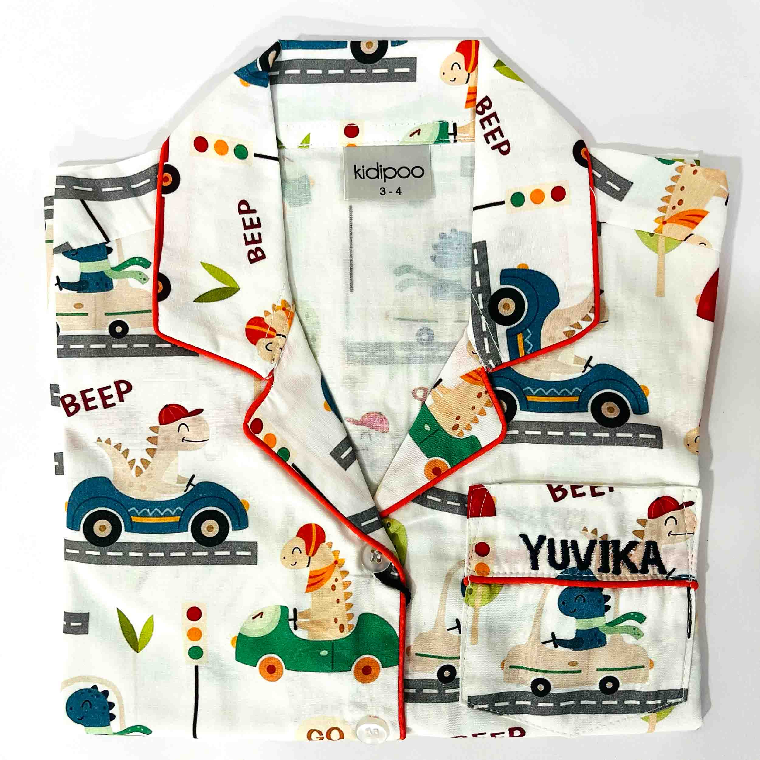 Children's outfit with vehicle and dinosaur pattern on a white background