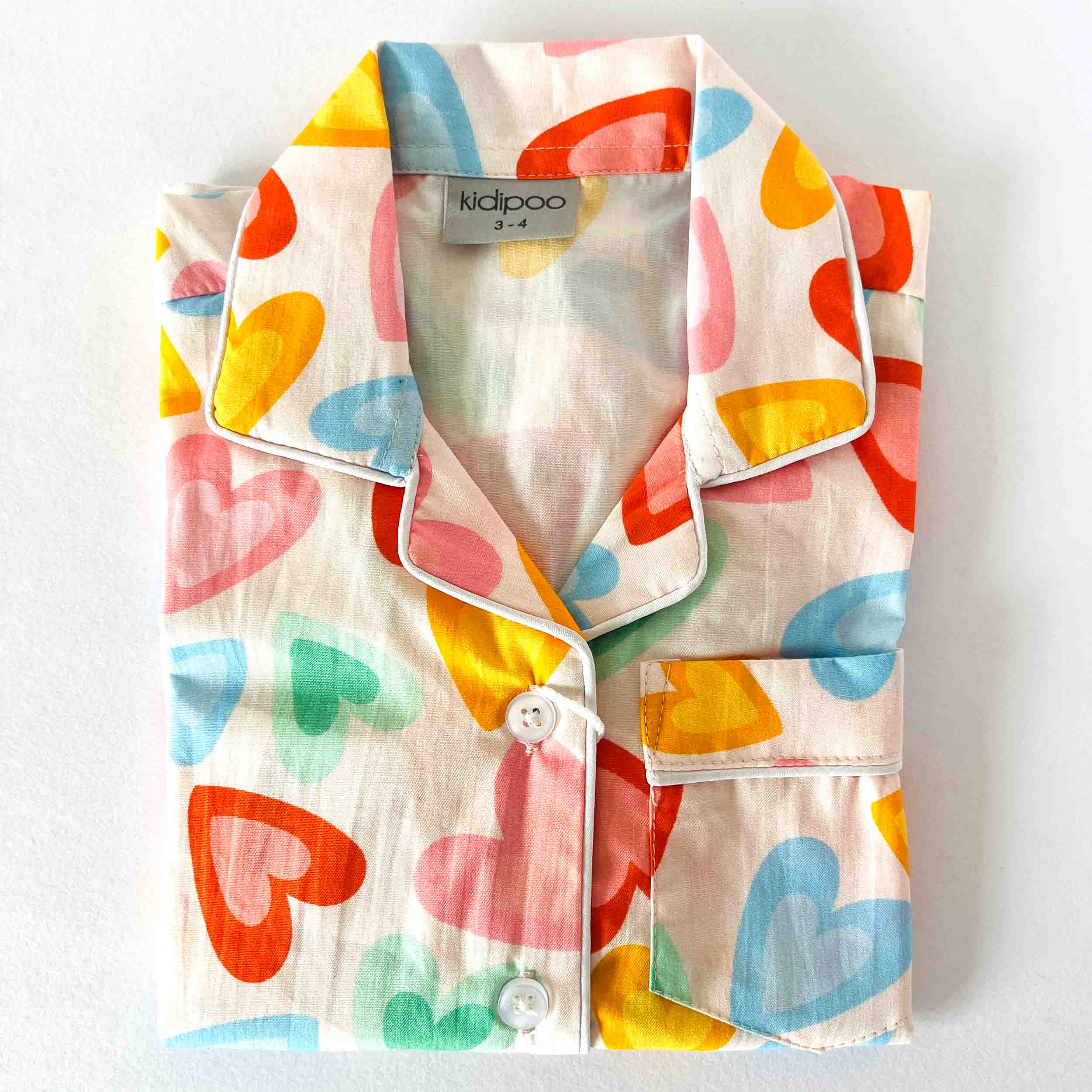 Colorful heart-patterned children's shirt with a 'kidpoo' label on a white background