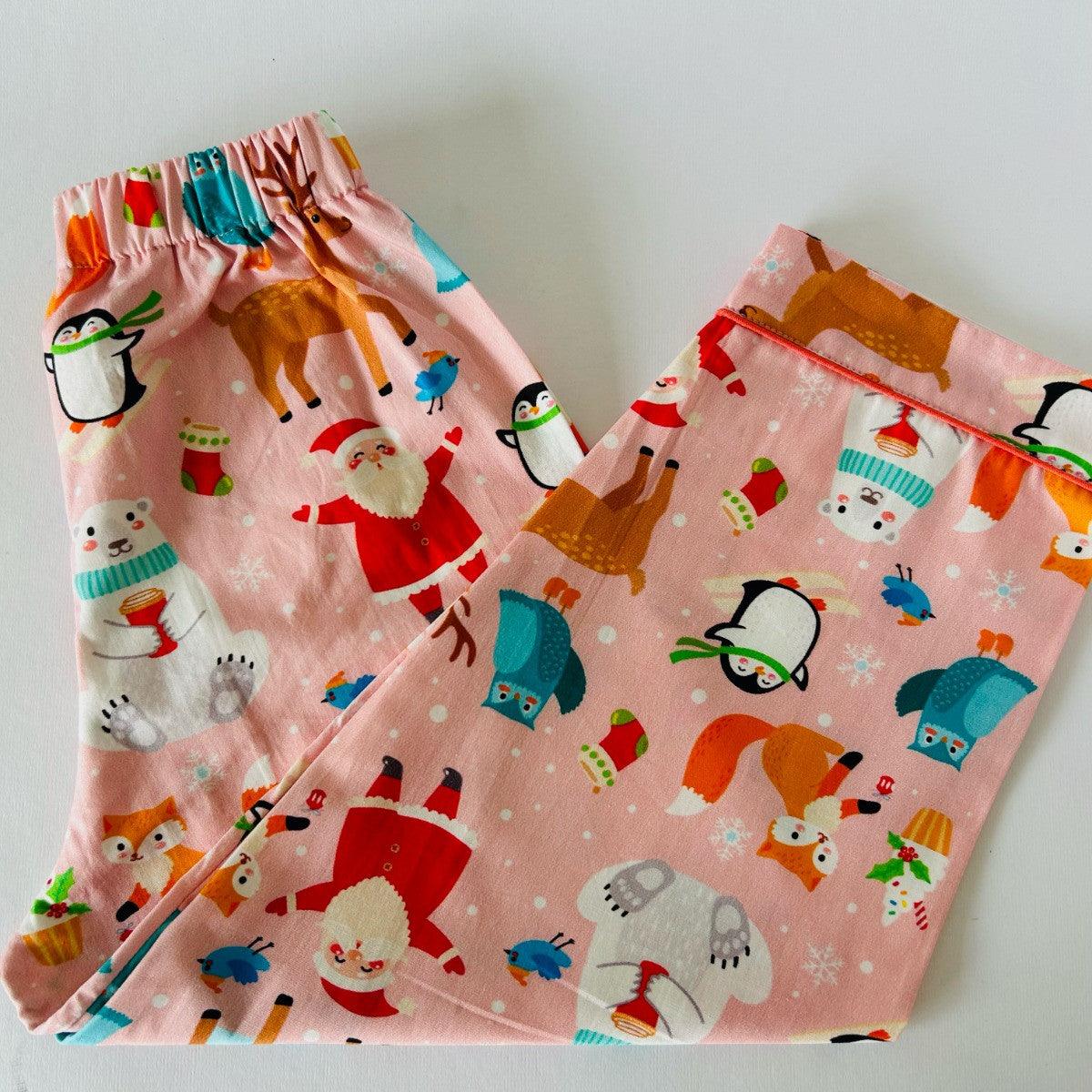 A pink night suit with a Christmas theme, featuring illustrations of Santa, reindeer, and snowflakes.
