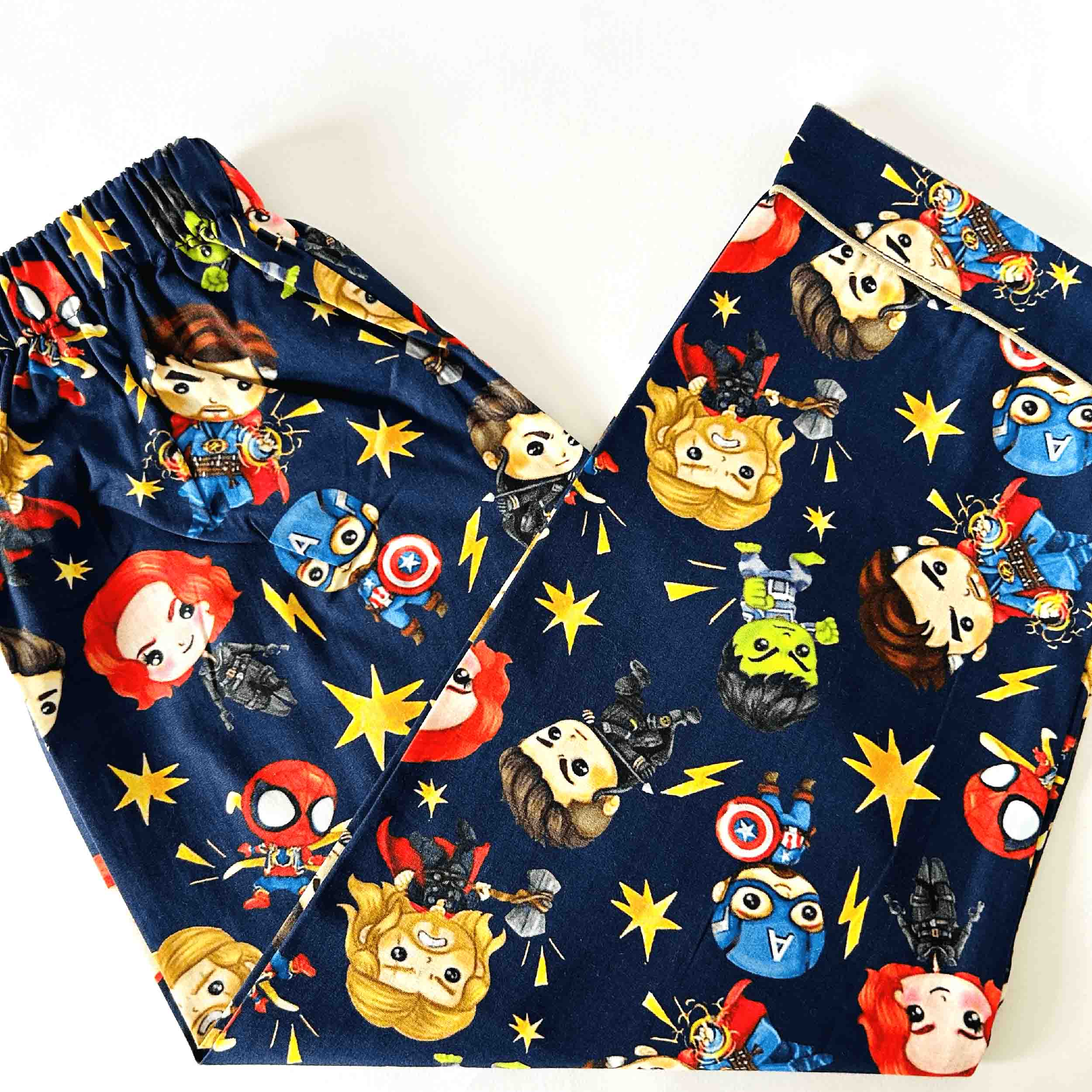 Pair of navy blue pajama pants with superhero-themed cartoon characters on a white background