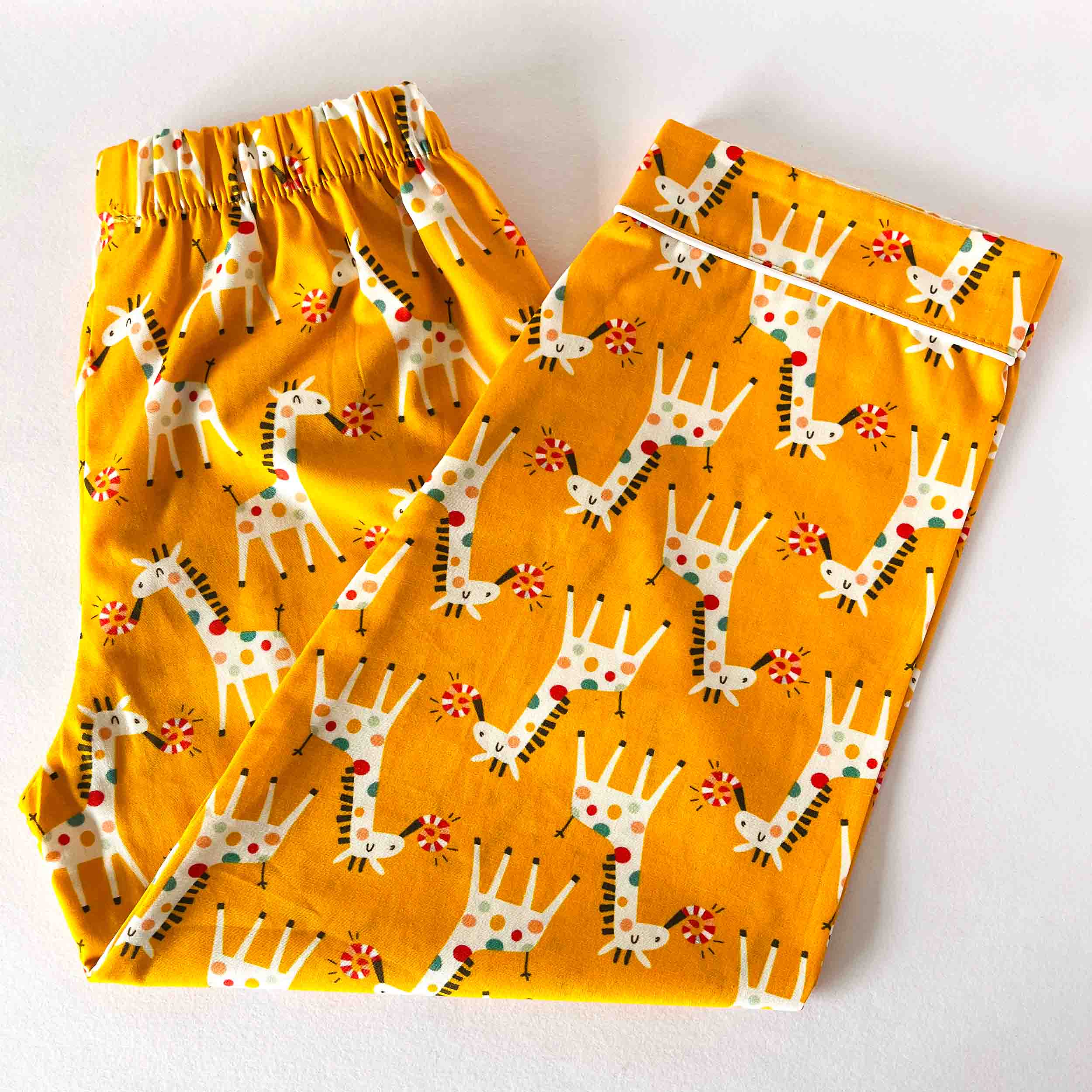 Pair of pajama pants with giraffe pattern on a yellow background