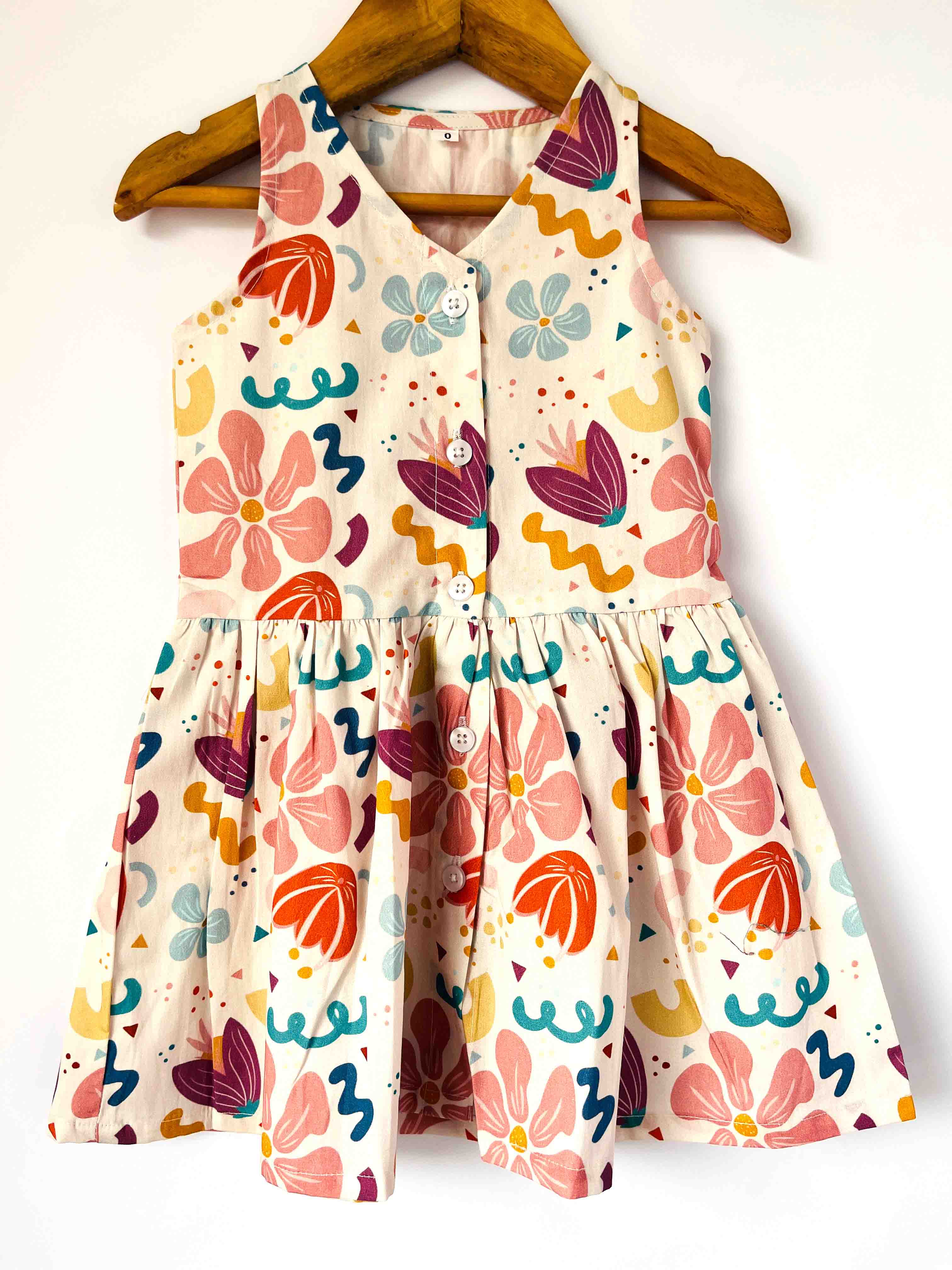 Colorful floral dress on a wooden hanger against a white background