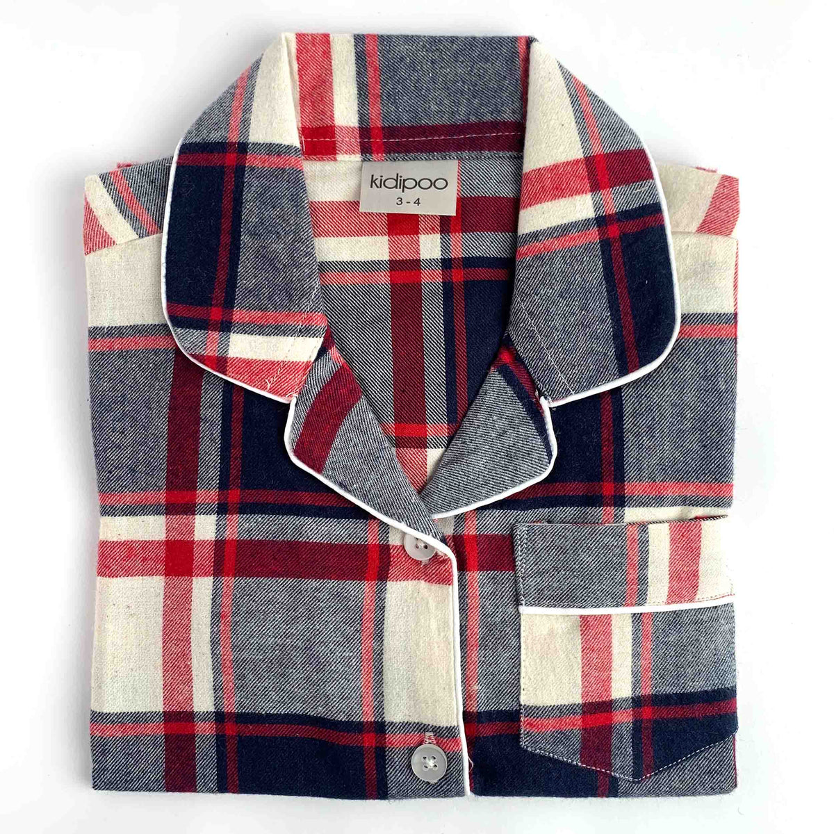 A folded plaid pajama shirt with a collar and button closure, shown on a plain white background. The fabric has a textured woven look with a plaid pattern in navy blue, red, and cream.