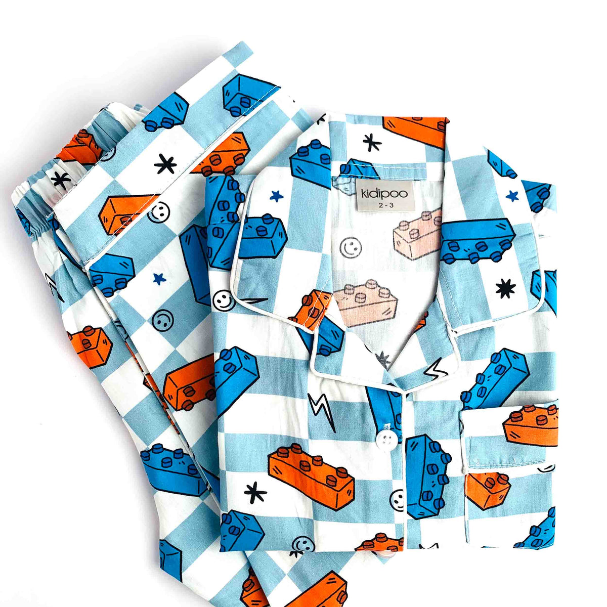 Children’s Block Buddy pajama set with light blue and cream checkered pattern, colorful blue, orange and peach building block prints, long-sleeve shirt and matching pants
