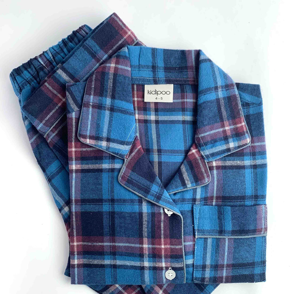 A folded pair of kids' plaid pajamas in blue, navy, and burgundy, featuring a button-down shirt and matching pants on a white background.