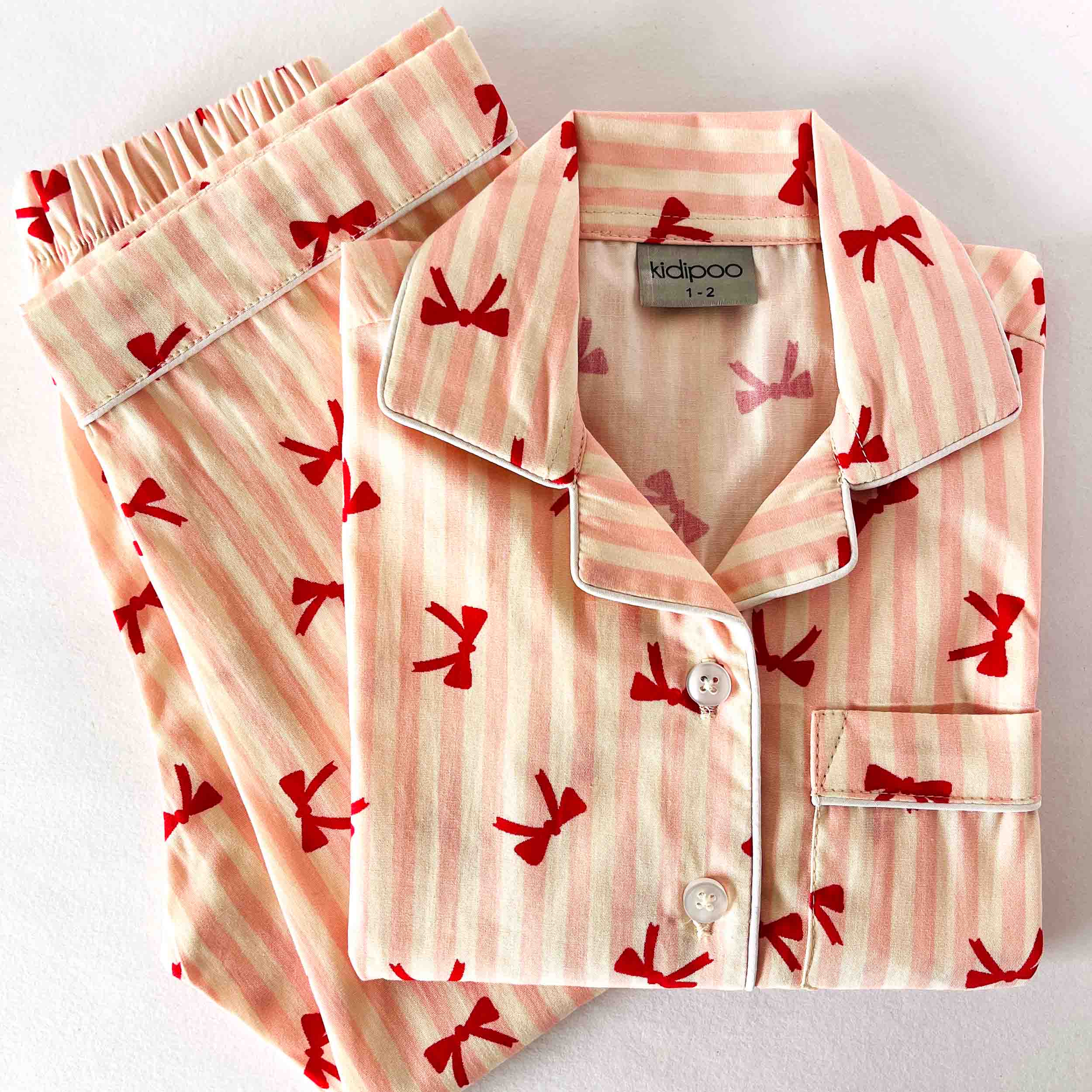 Pink pajama set with red bow pattern on a white background