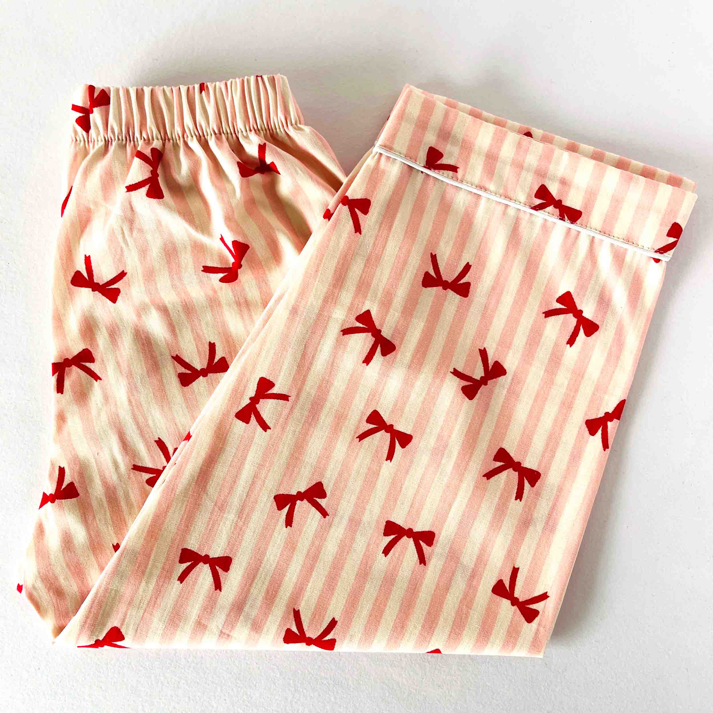 Pair of pajama pants with red bow pattern on a white background