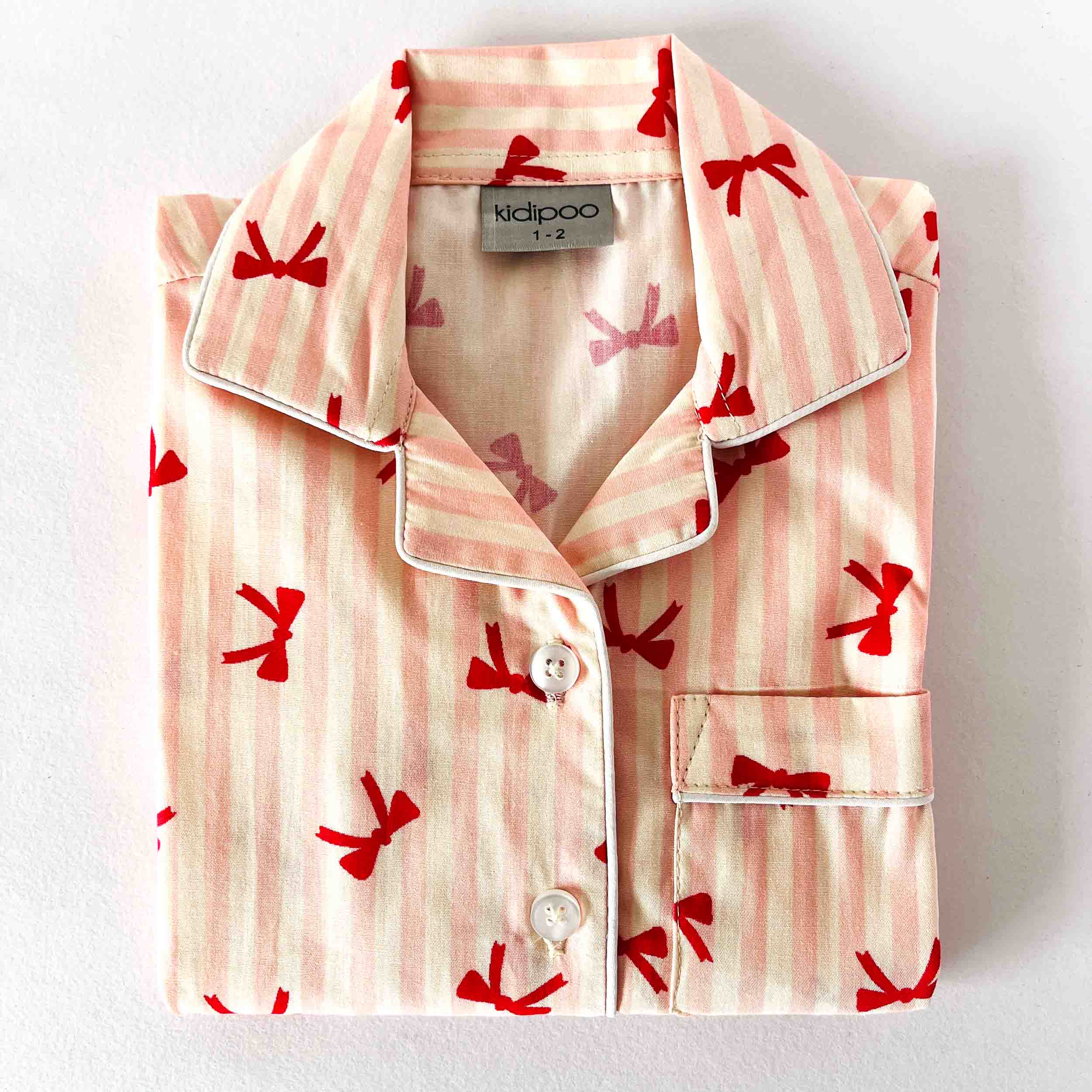 Pink pajama top with red bow pattern on a white background