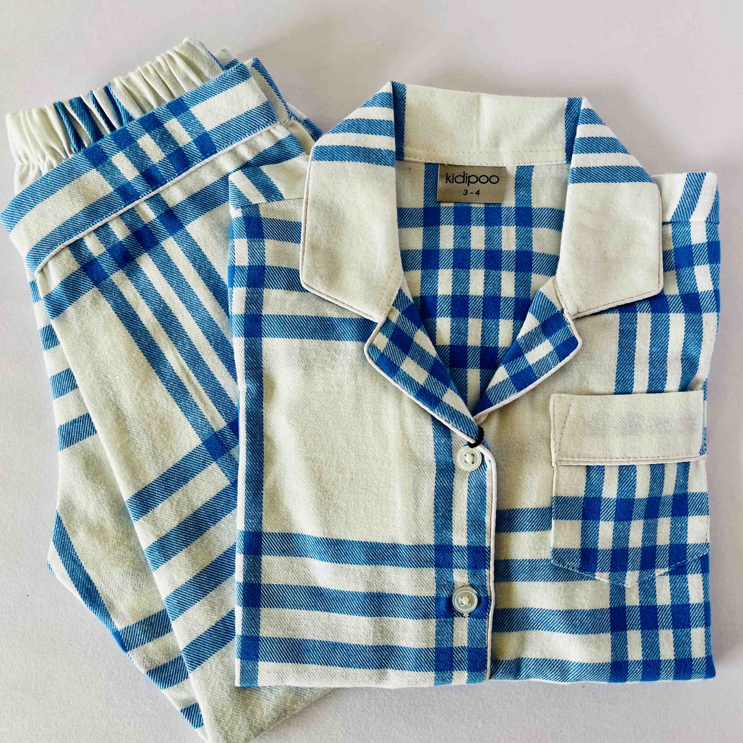 Blue and white checkered pajama set with a shirt and pants on a light gray background