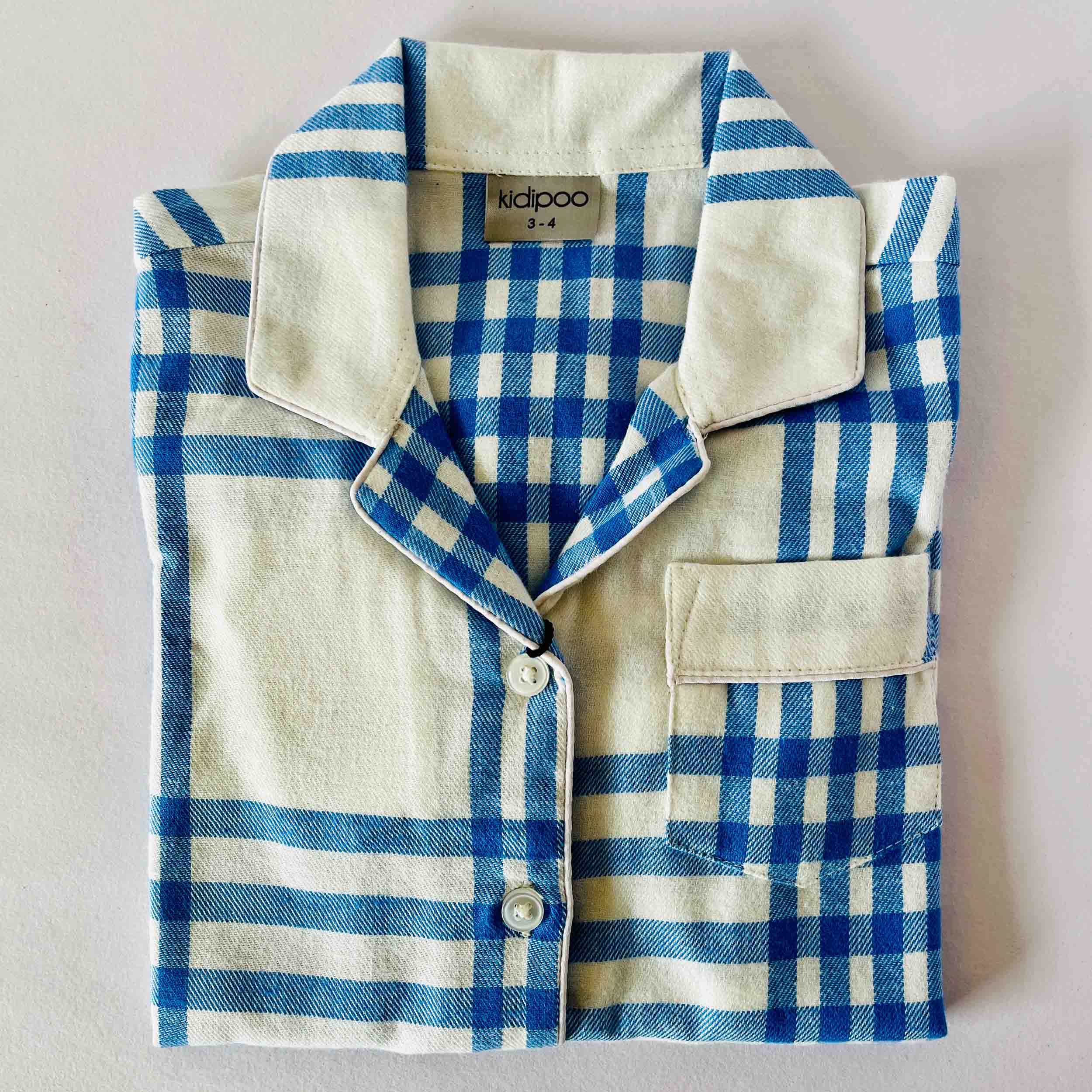 Blue and white checkered shirt with 'kidpoo' label on a light gray background