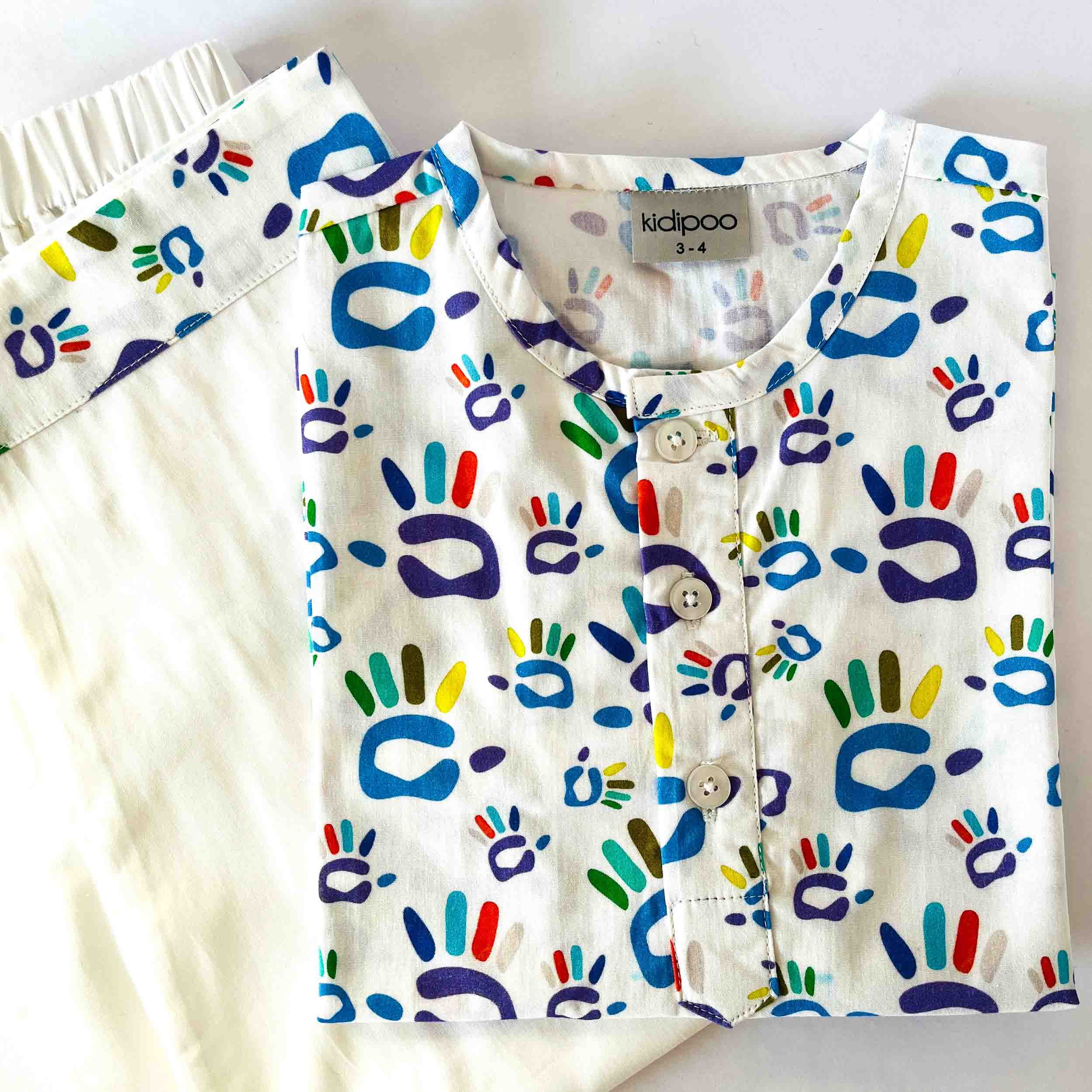 Children's shirt with colorful hand and shoe prints on a white background