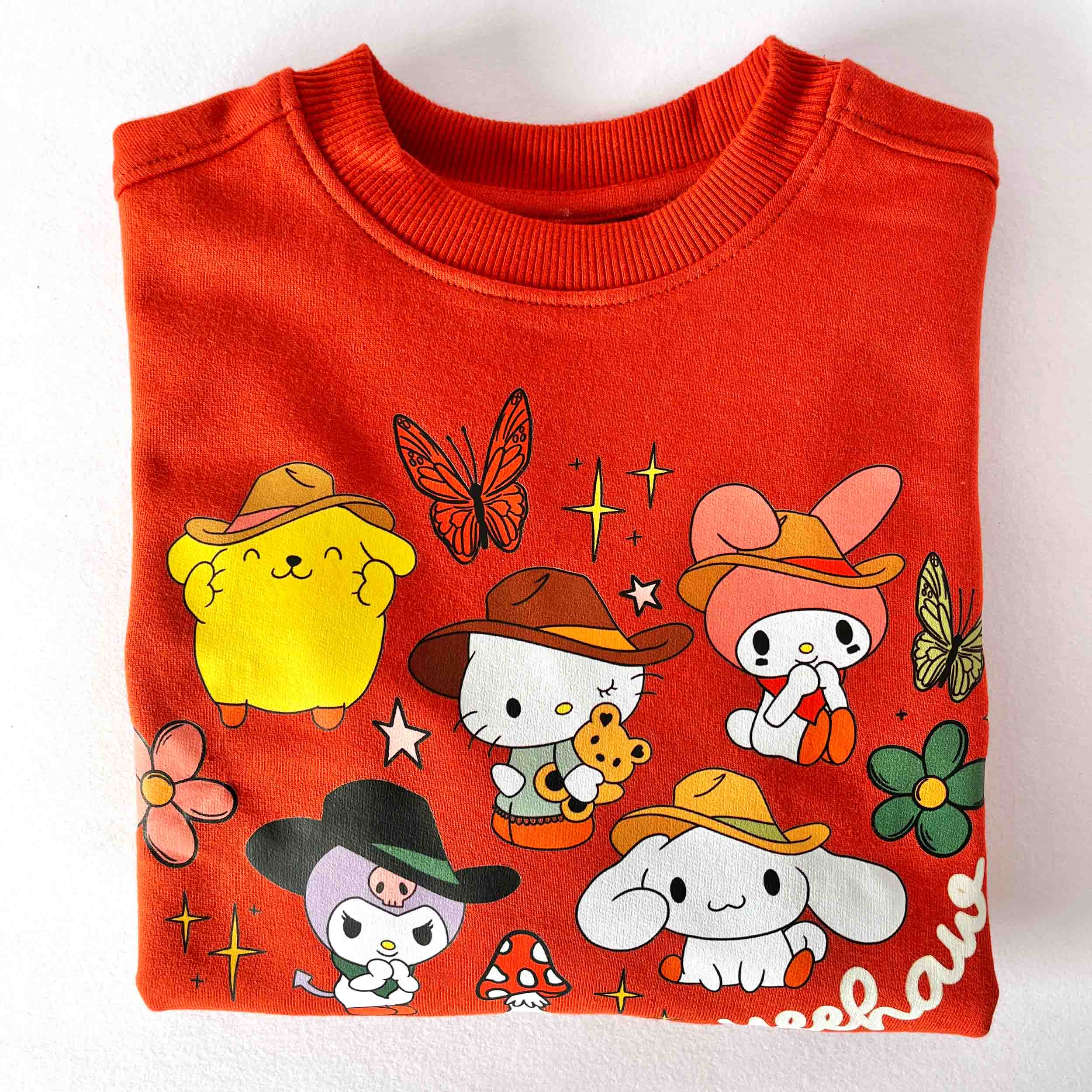 Folded red sweater with cartoon characters and designs on a white background