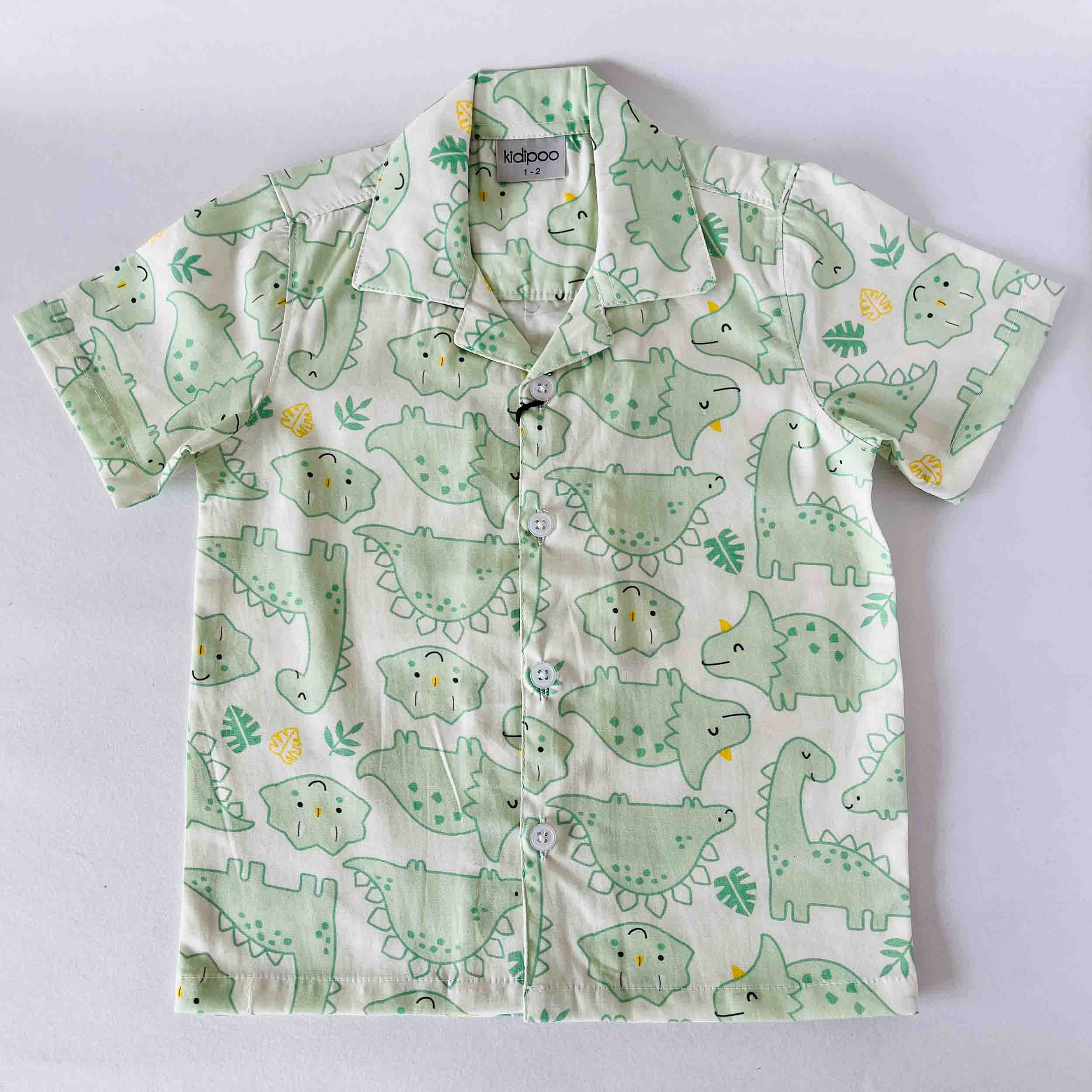 Children's shirt with green dinosaur pattern on a light gray background
