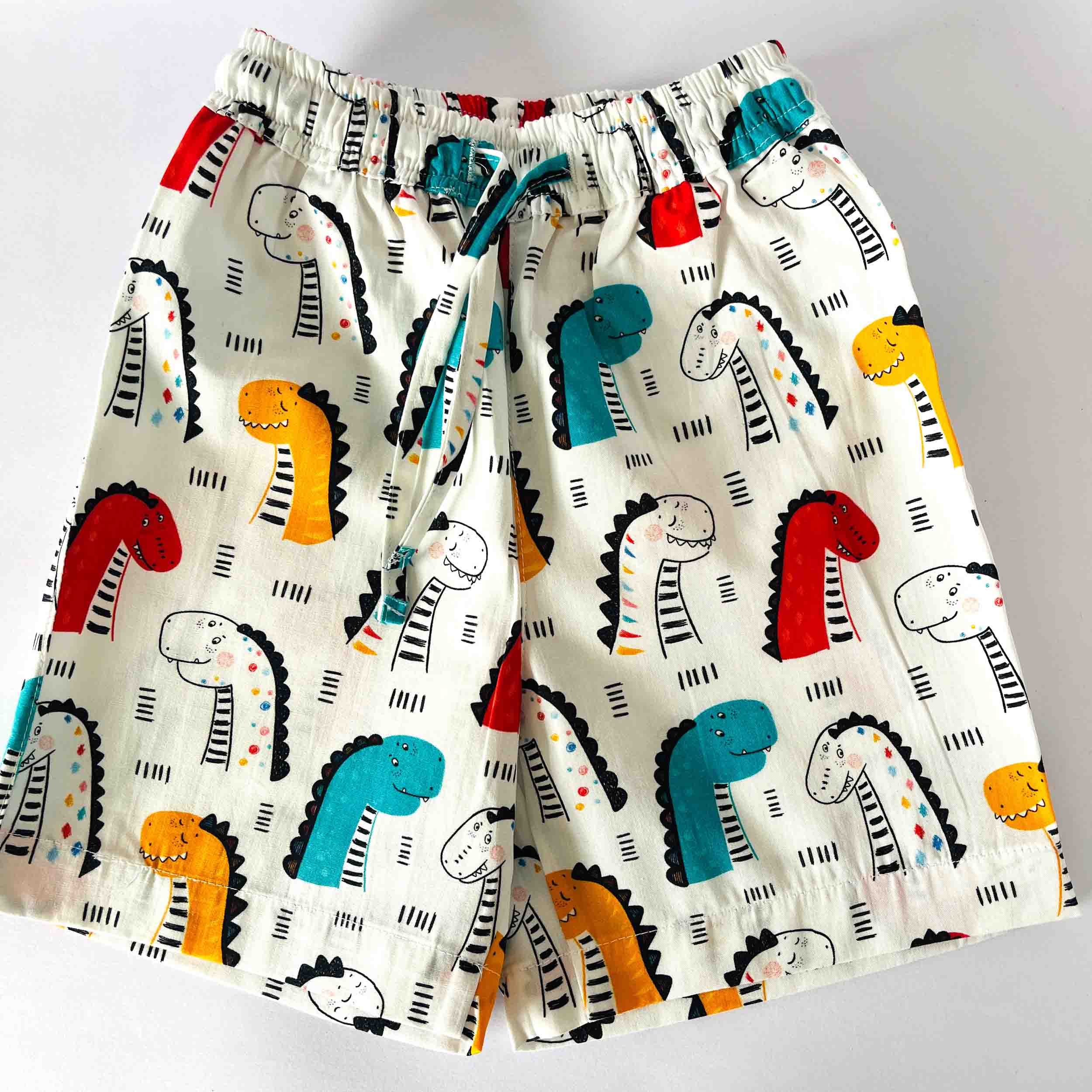 Children's shorts with colorful dinosaur pattern on a white background