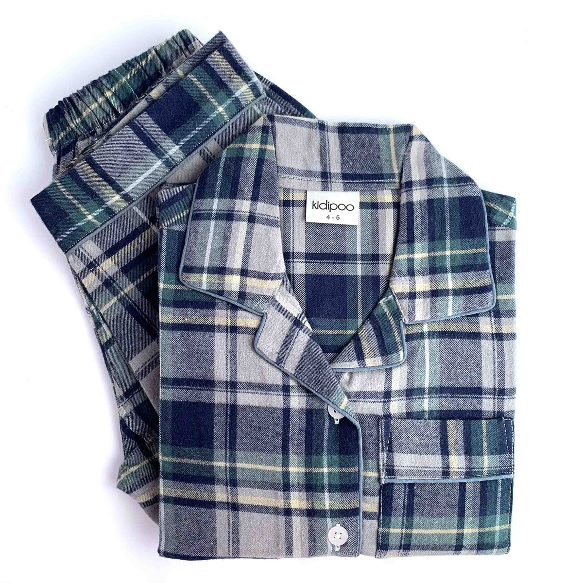A folded plaid pajama set on a white background, featuring a long-sleeve button-front pajama shirt with a matching pair of pajama. The fabric has a classic plaid pattern in navy blue, gray, green, and beige.