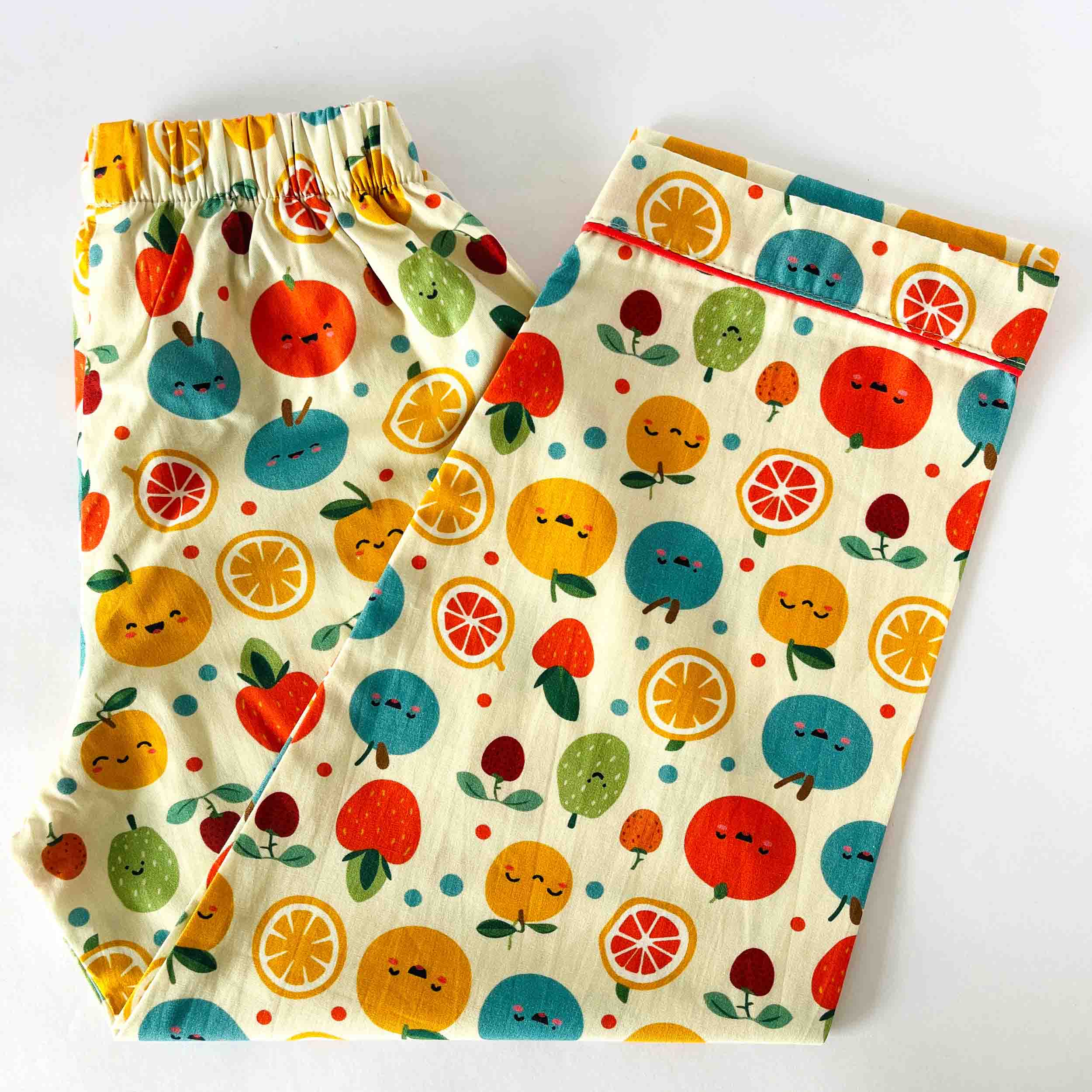 Two pairs of colorful fruit-patterned shorts on a white background