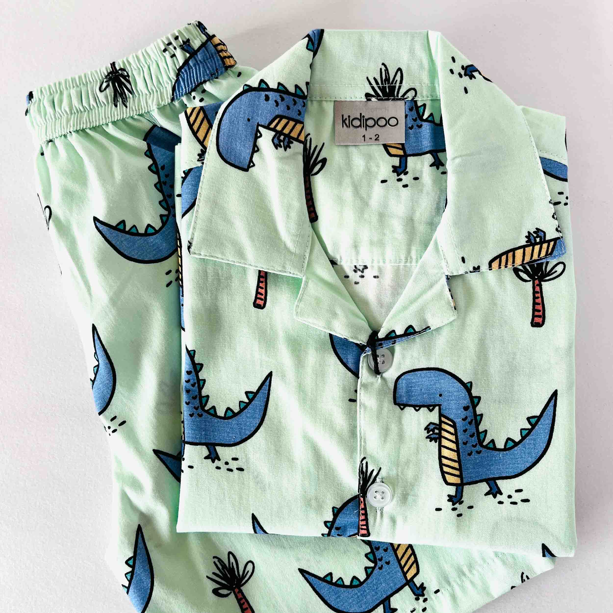 Light green children's pajama set with dinosaur pattern.