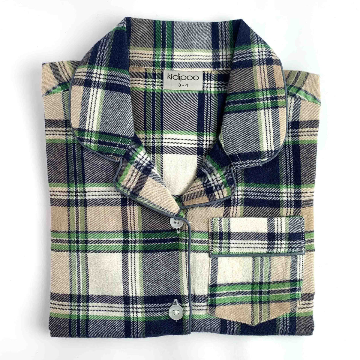 A folded plaid pajama shirt with a collar and button front, shown on a plain white background. The fabric has a tartan pattern in beige, navy, gray, and green, with a visible neck label reading 'kidipoo'.
