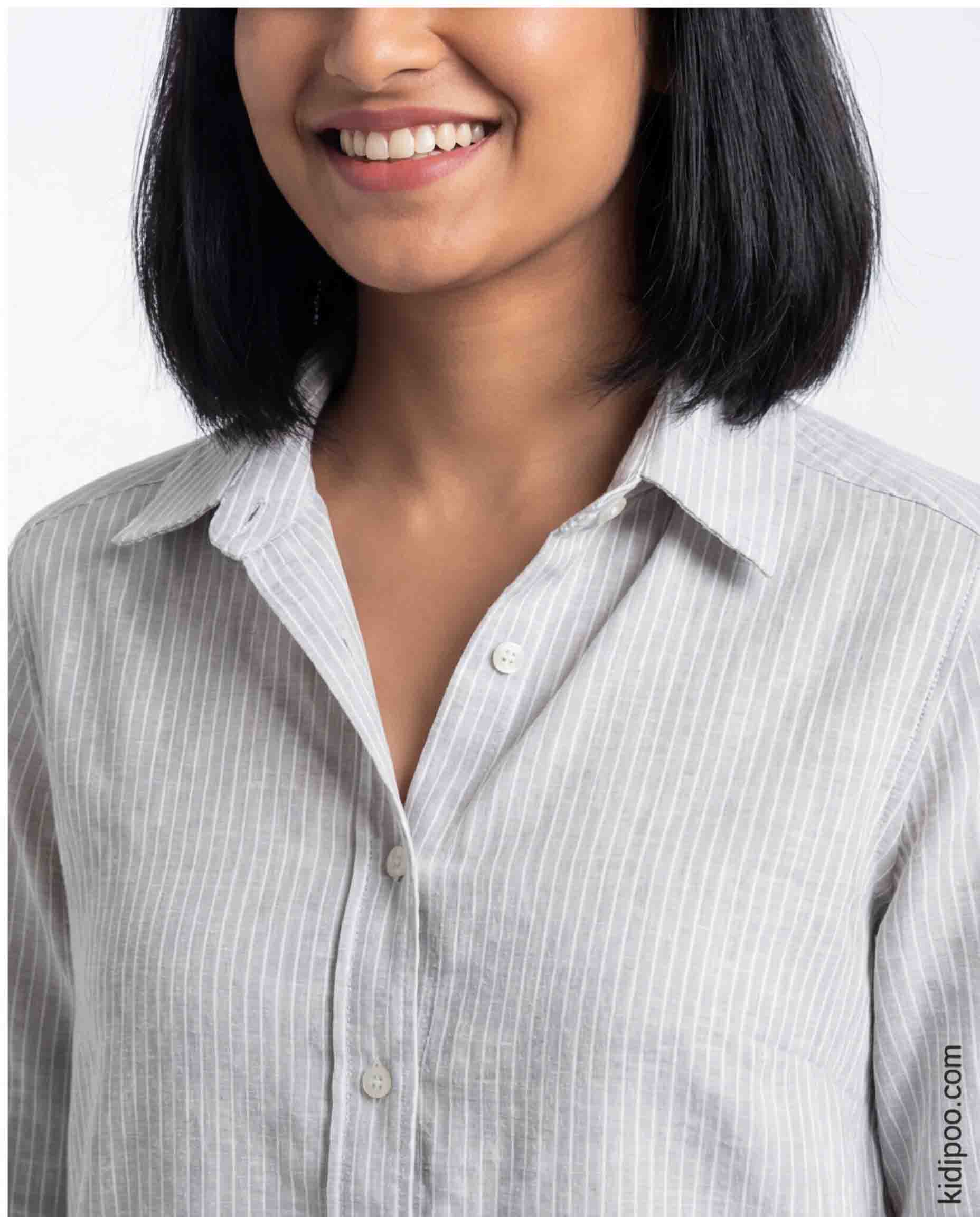 Woman wearing a light gray striped shirt against a white background