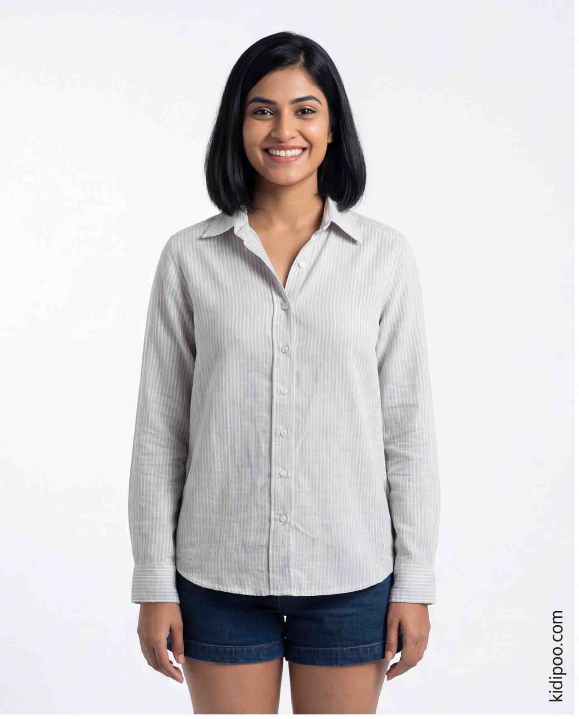 Woman wearing a light gray button-up shirt and dark shorts on a white background