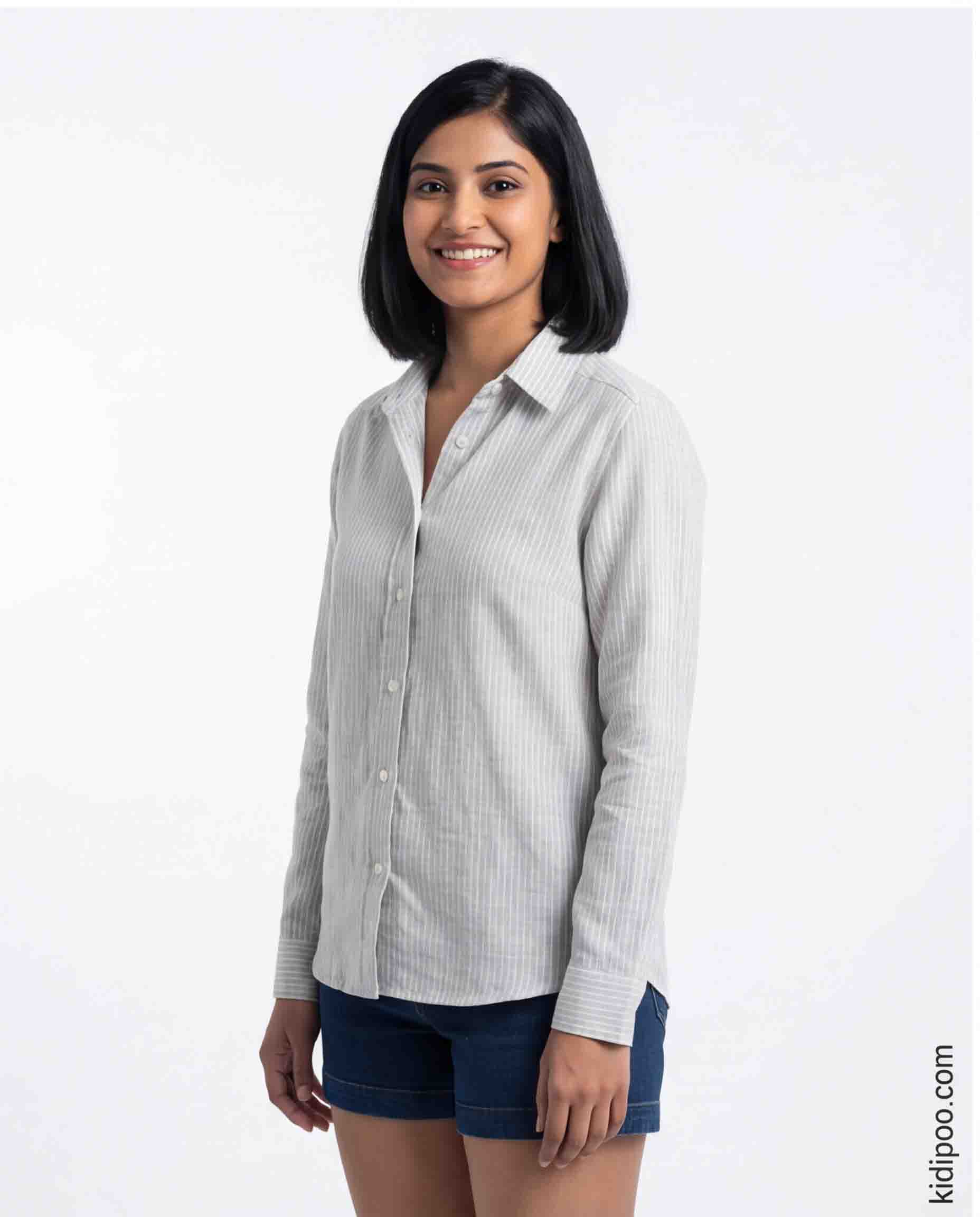 Woman wearing a light gray striped shirt and dark shorts on a white background
