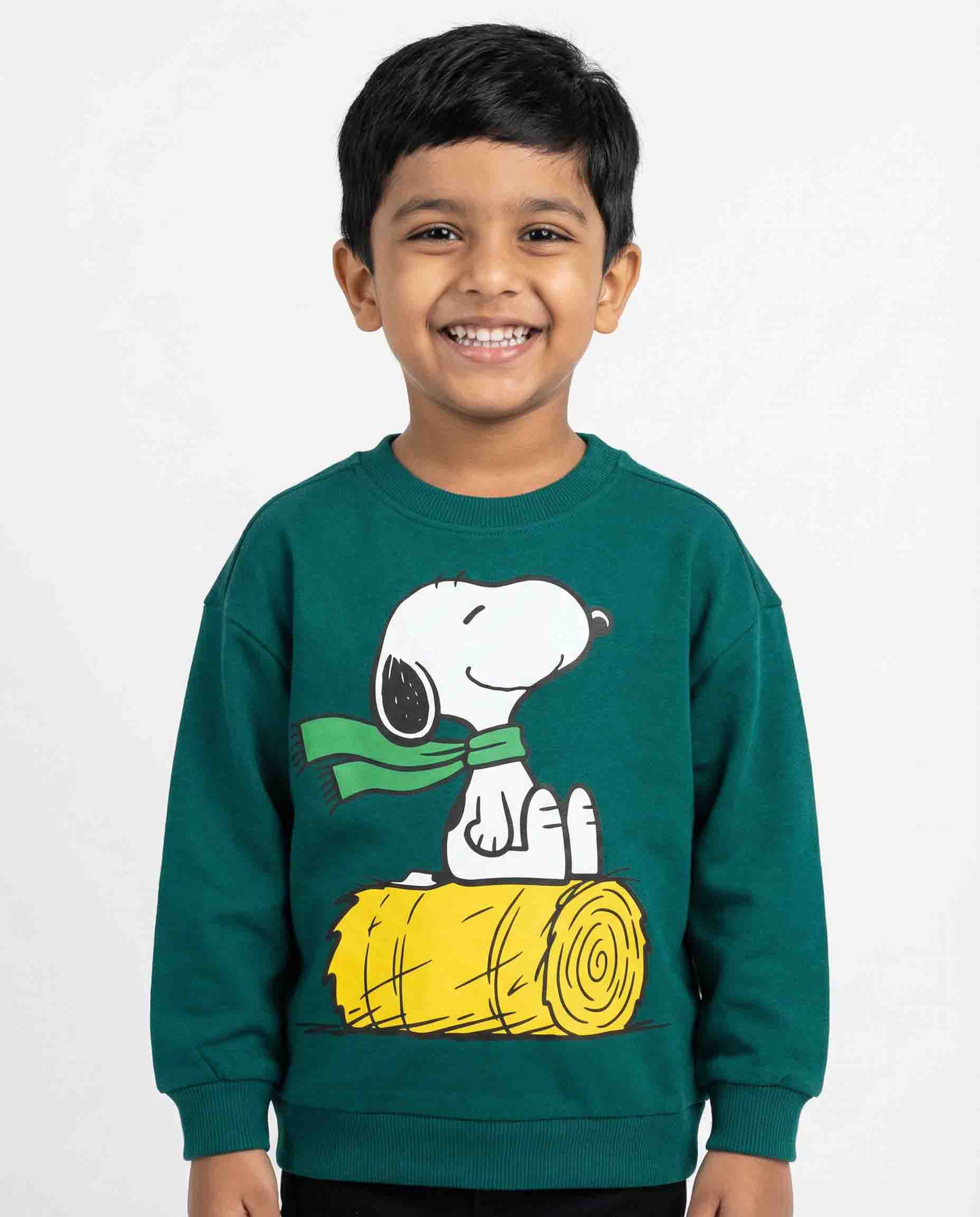 Child wearing a green sweatshirt with a cartoon character on a white background