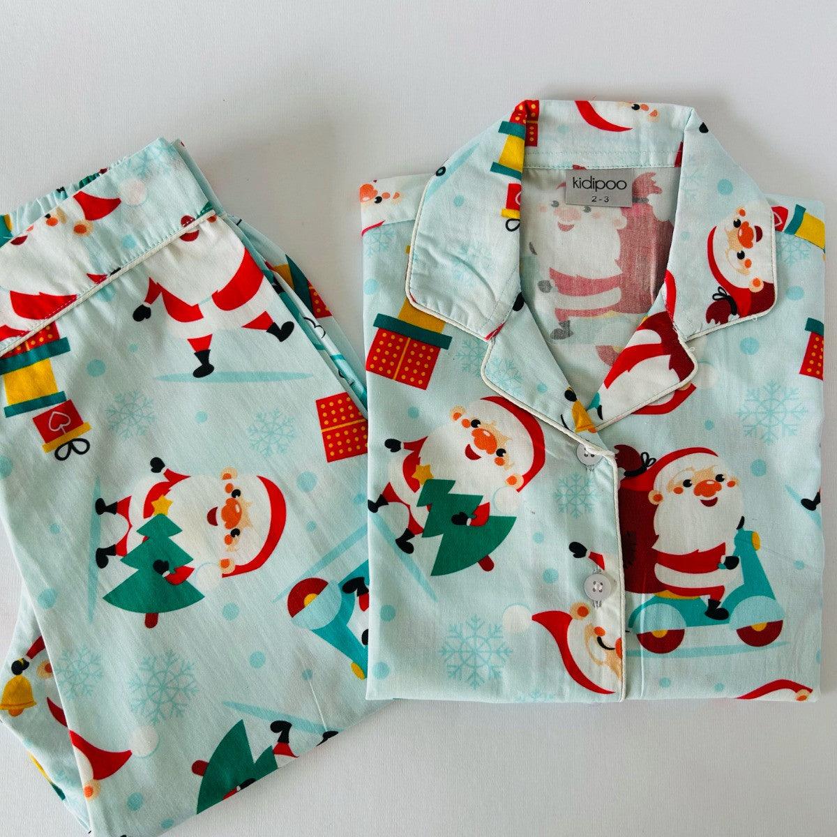 A Christmas-themed sleepwear set, consisting of a long sleeve shirt and pajamas, with Santa Claus and holiday motifs on a light blue background.