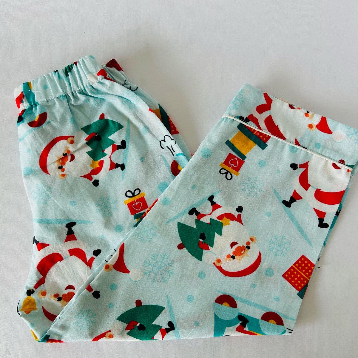 A Christmas-themed sleepwear set, consisting of a long sleeve shirt and pajamas, with Santa Claus and holiday motifs on a light blue background.