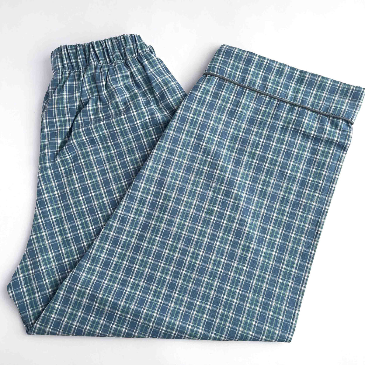 A pair of folded plaid pajama pants in blue and white, featuring an elastic waistband, laid flat on a white background.