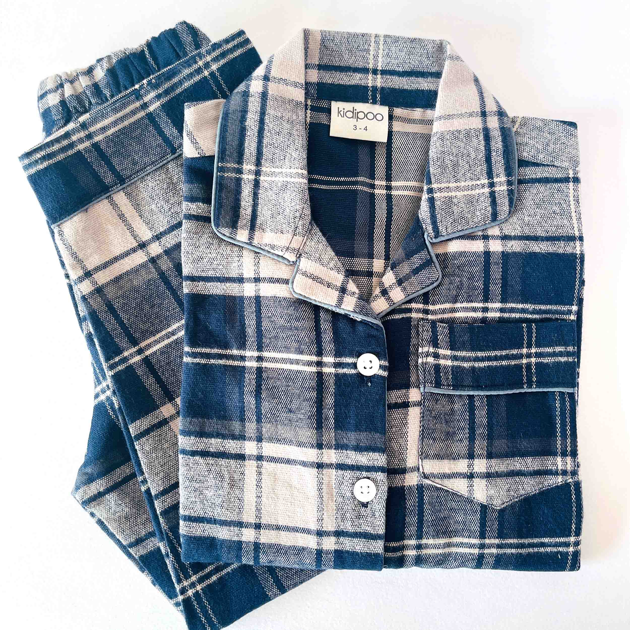 Folded blue and white plaid pajama set with 'kidpoo' label on a white background