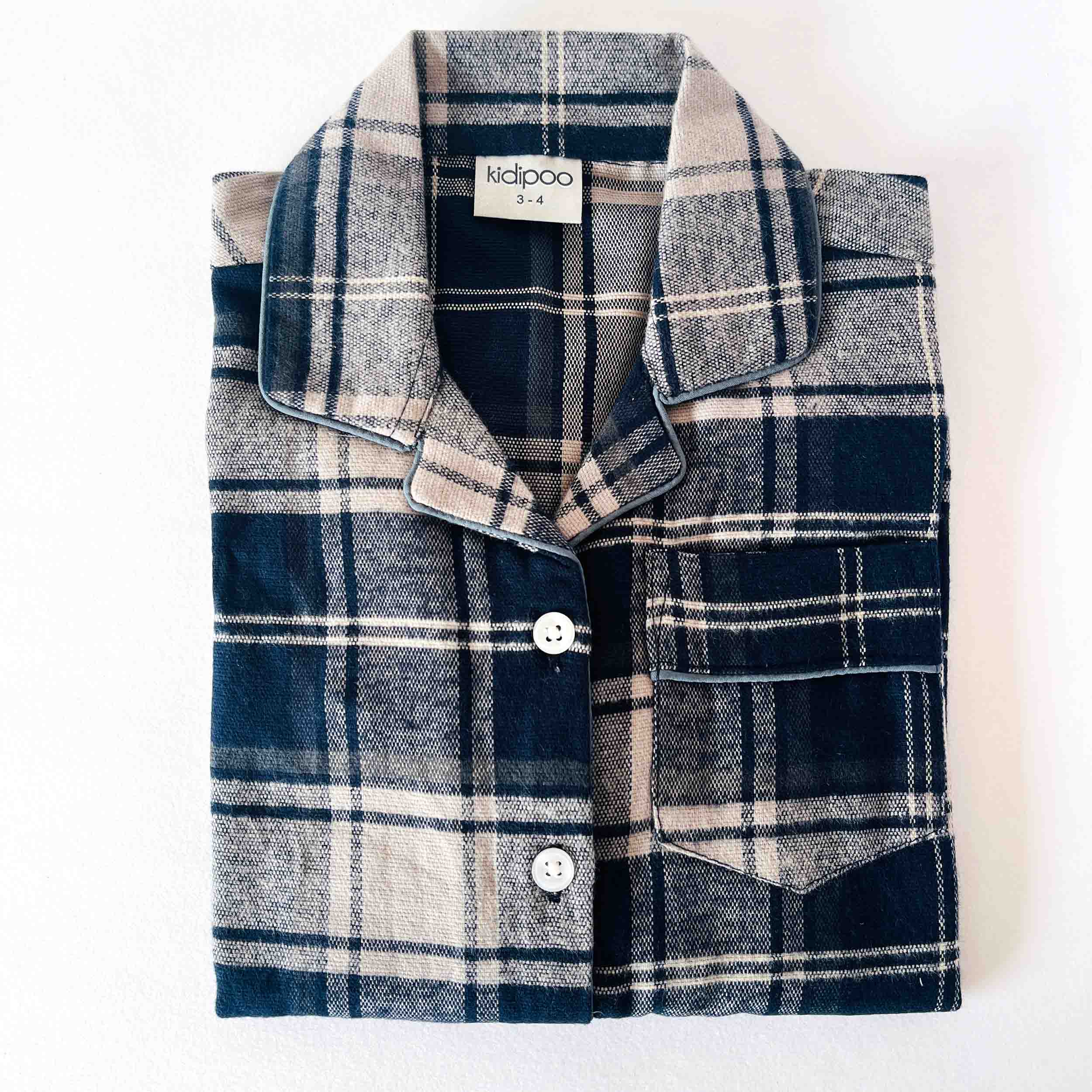 Folded plaid shirt with a visible brand label on a white background