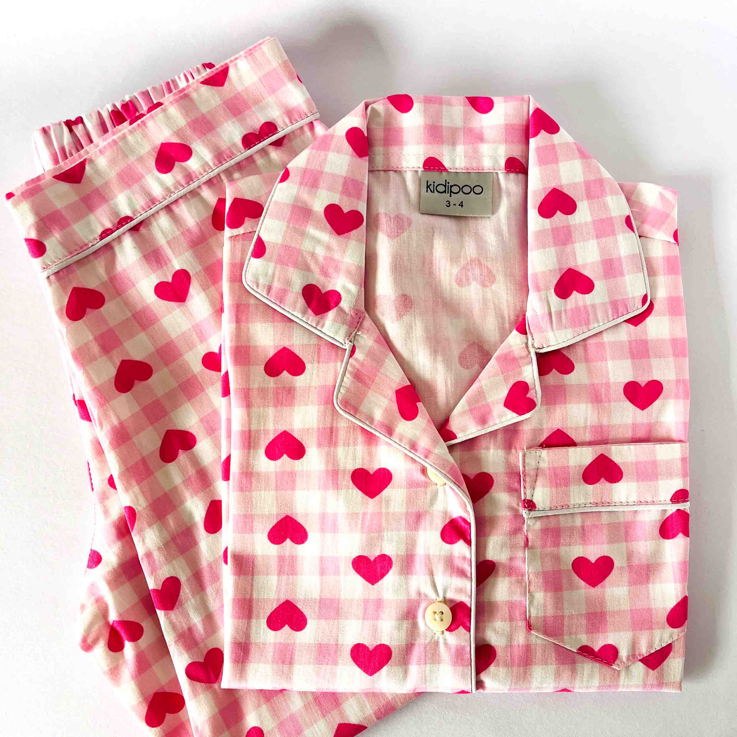 Pink checkered pajama set with heart patterns on a white background