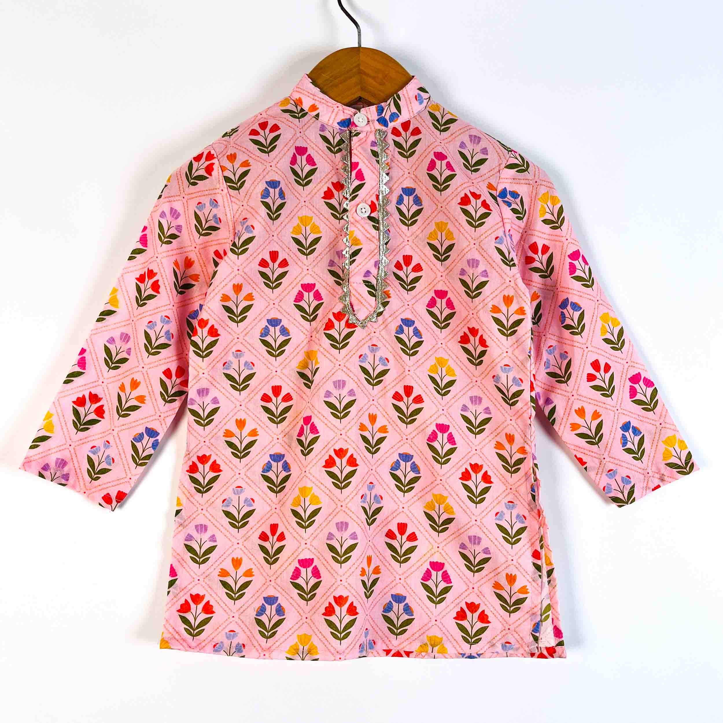 A pink long-sleeve kurta with a colorful floral pattern, hanging on a wooden hanger against a plain white background.